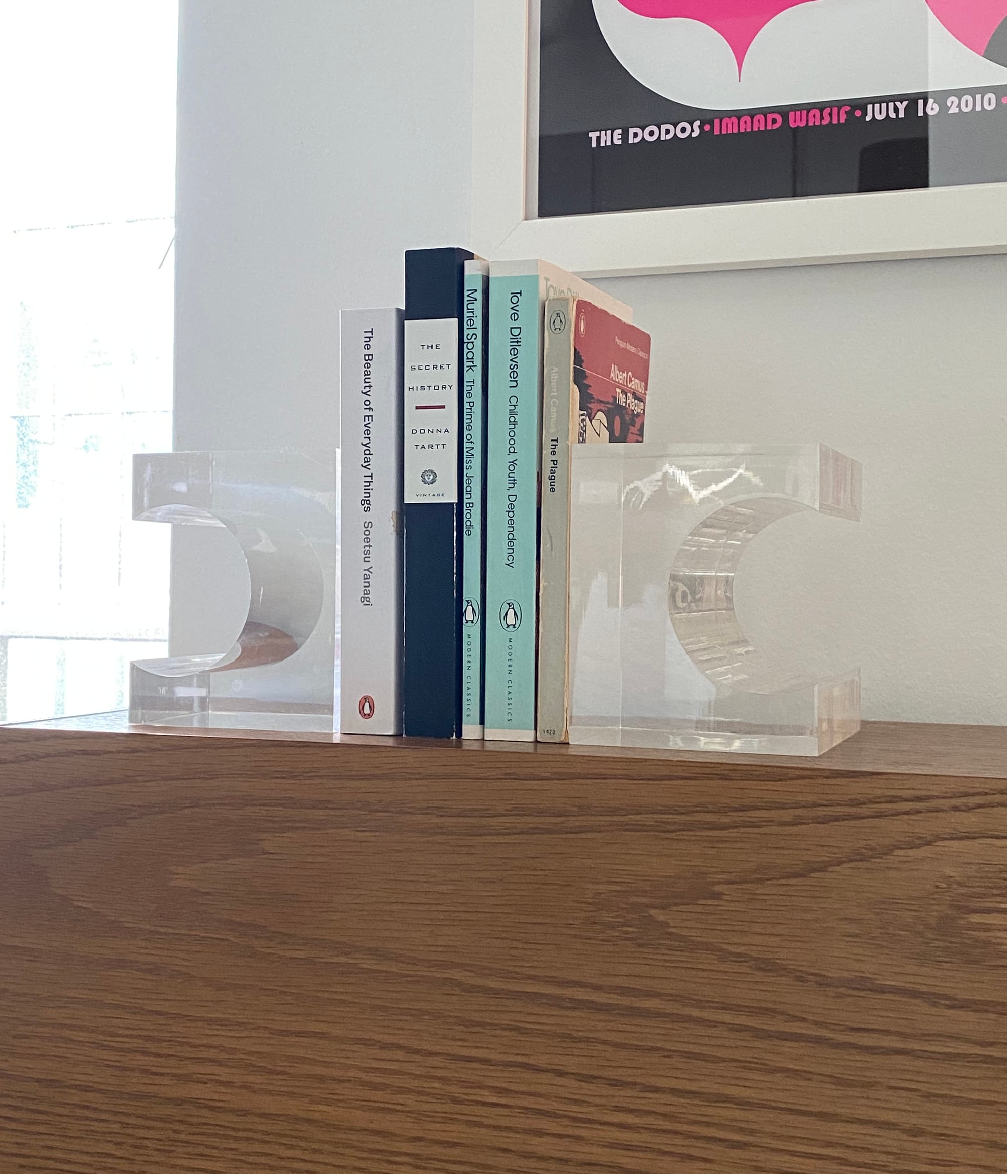 Five paperback books held upright by two Lucite bookends.