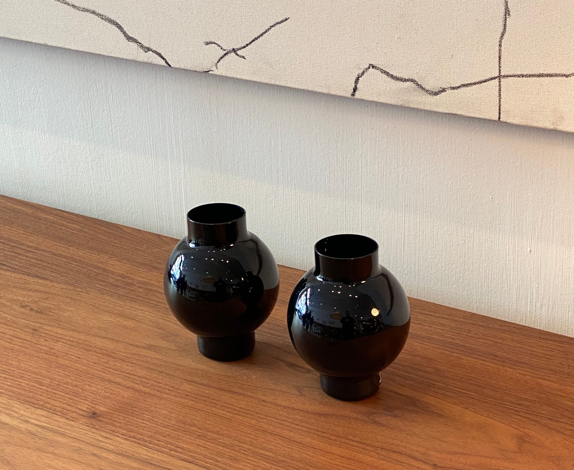Two glossy black vases on a wooden surface.