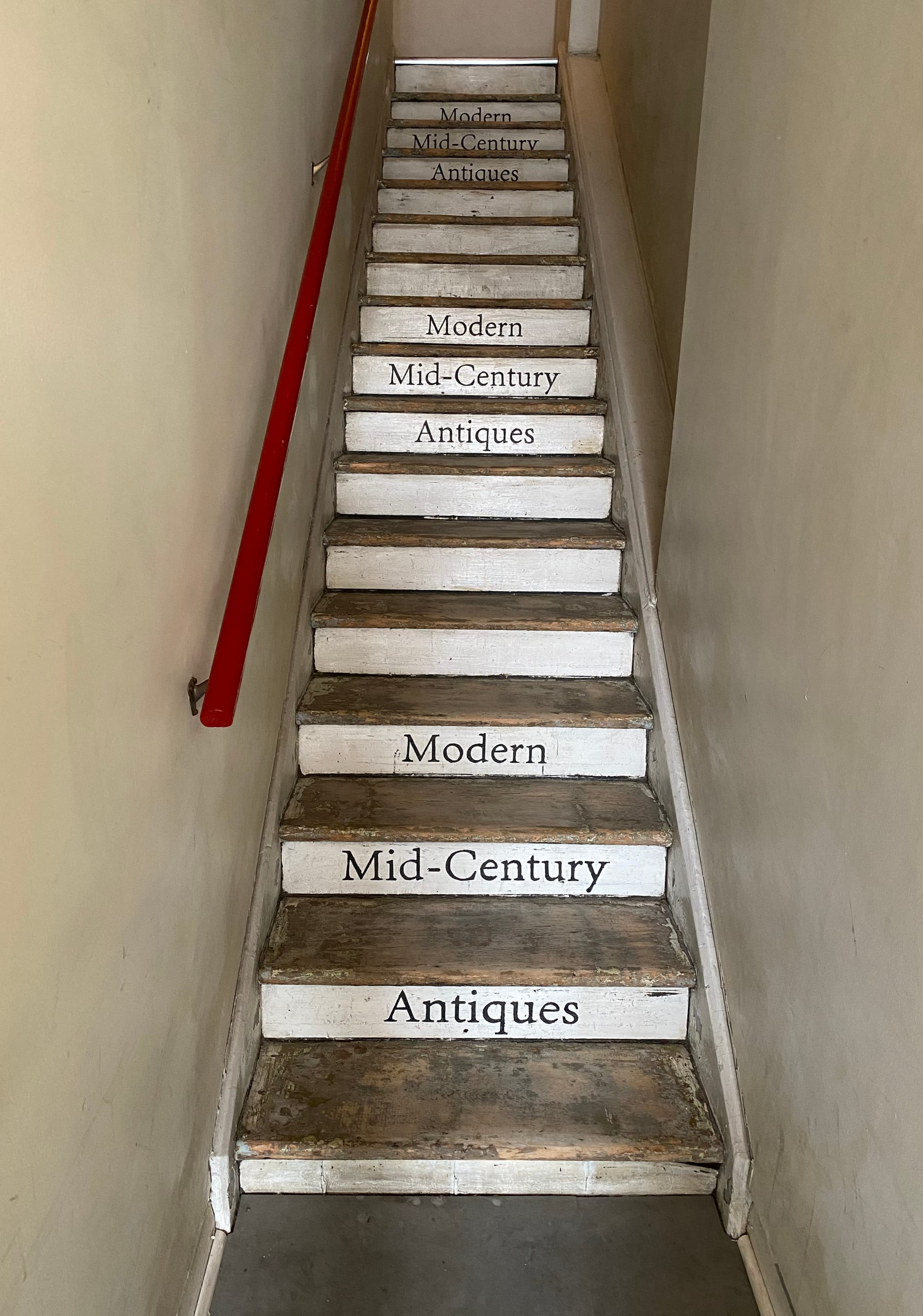 Staircase leading to the second floor shop with the phrase "Modern Mid-Century Antiques" appearing three times on the risers.