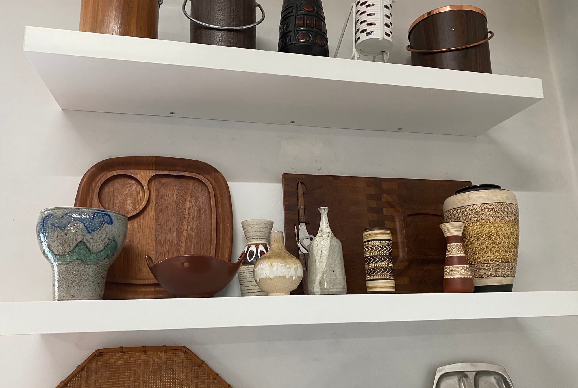 Pottery vases and teak objects on a shelf.