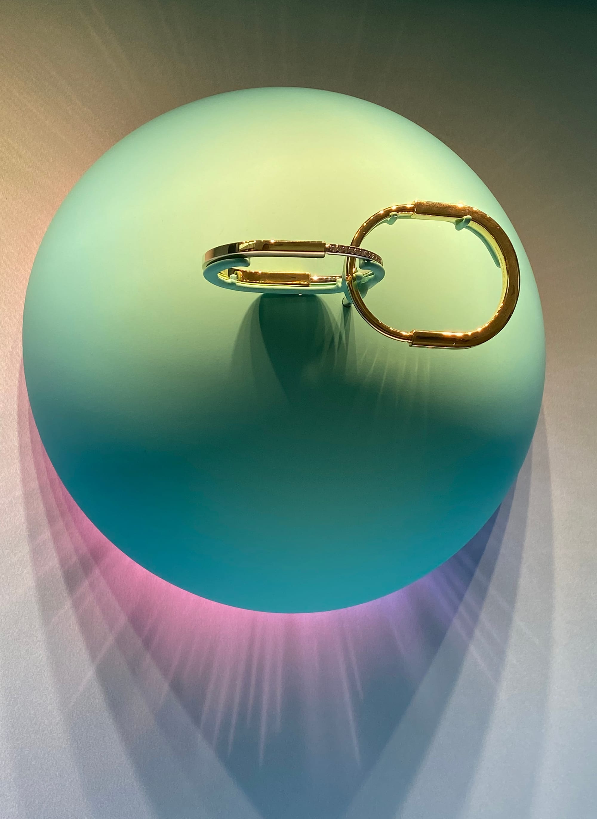 Green semi-sphere with linked bracelets mounted on its surface.