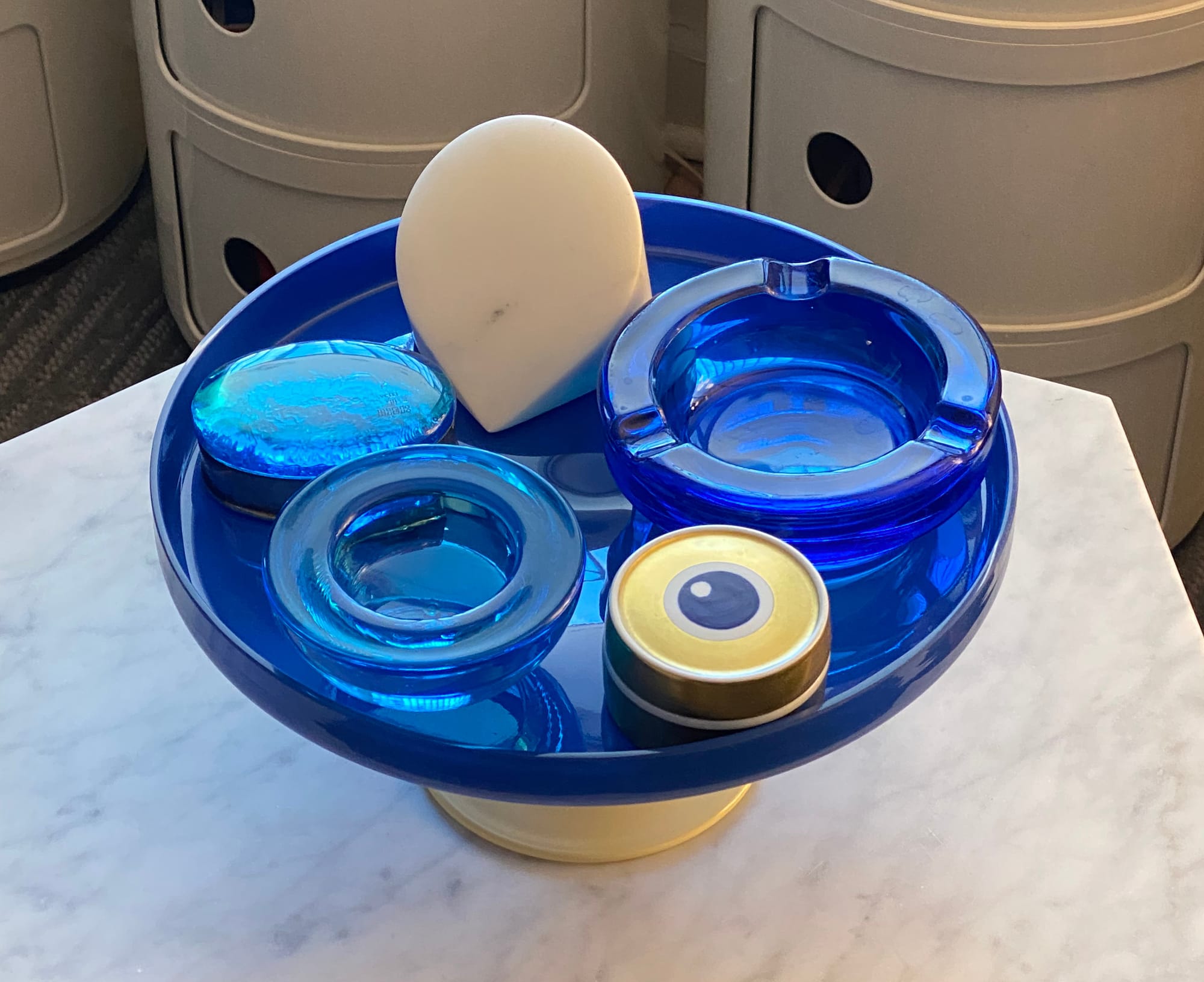 Cakestand holding assorted objects, including an ashtray and a paperweight.