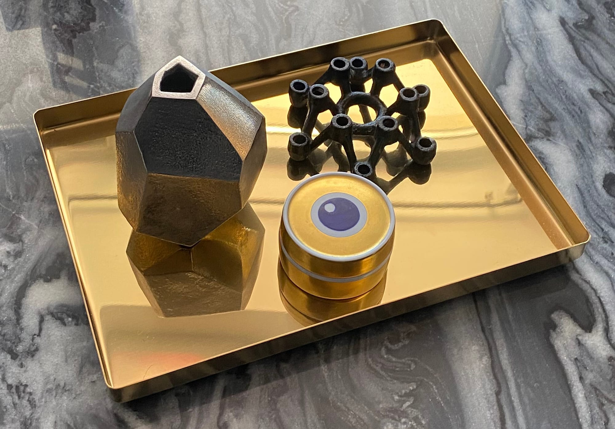 Brass-coloured tray displaying vase, candle holder and trinket box.