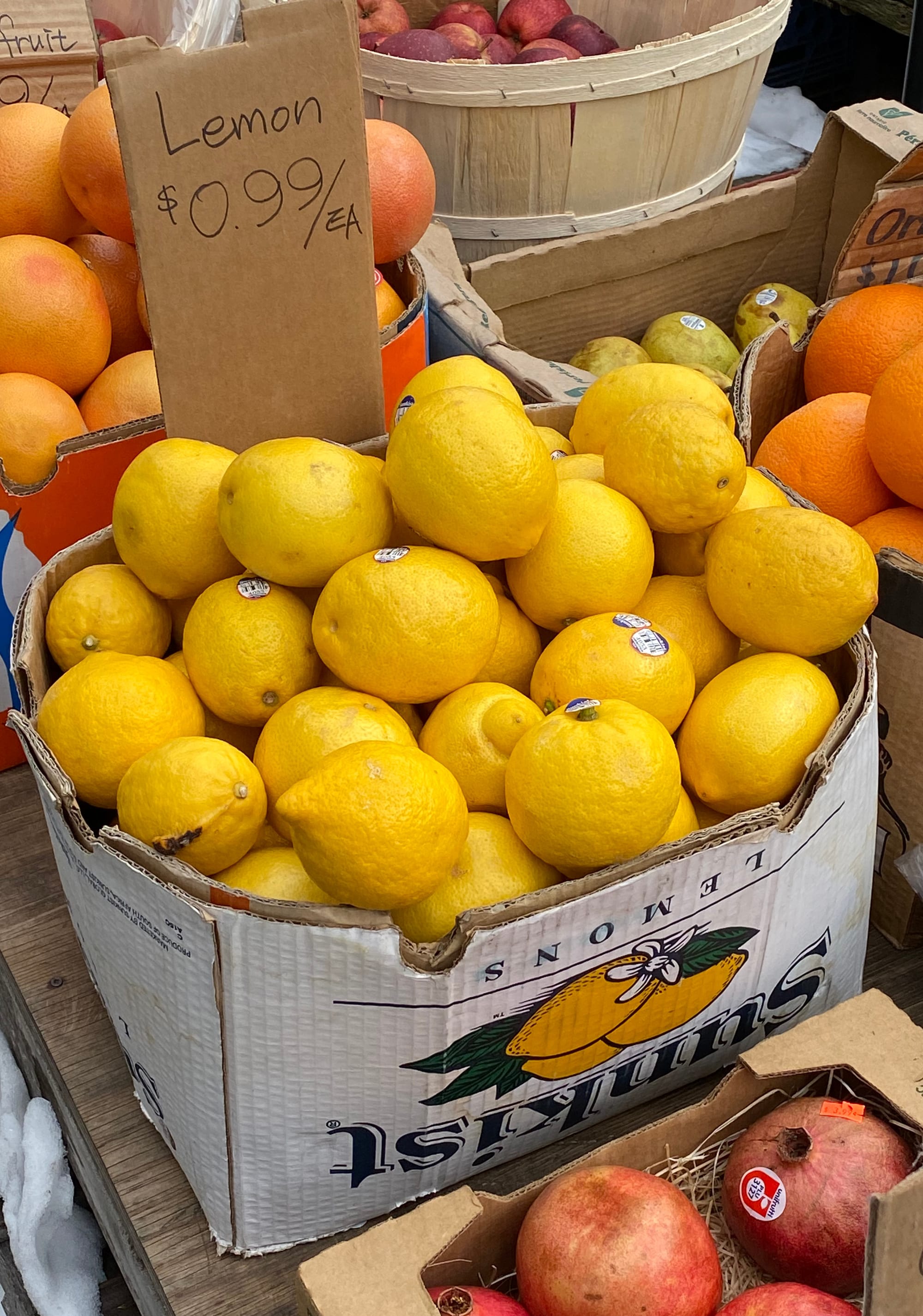 Box of lemons that is almost overflowing.