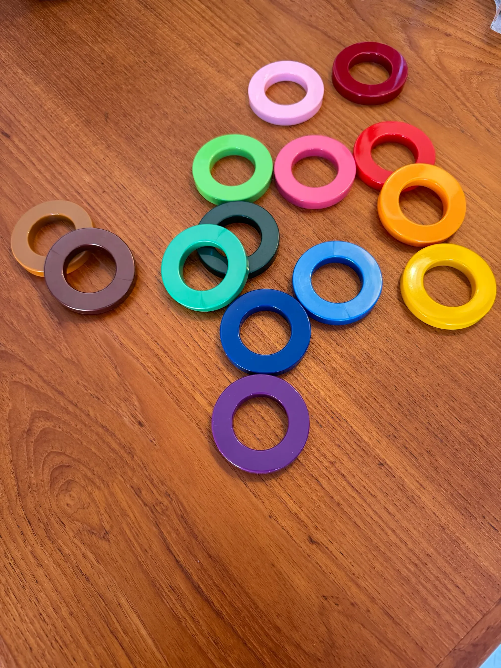 Fourteen rings, each with a unique colour, displayed on a table top.