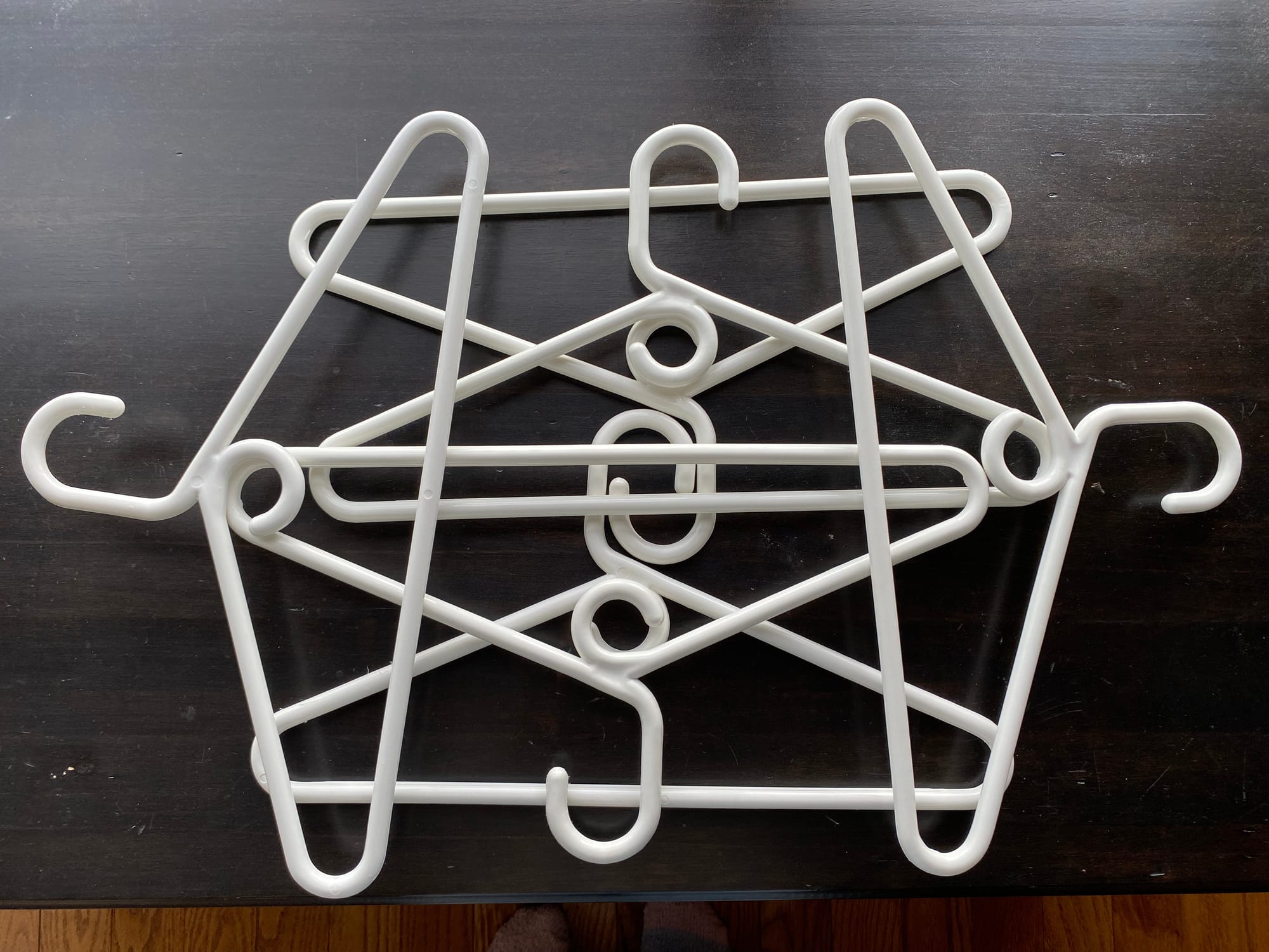 Six white plastic hangers layered on top of each other.