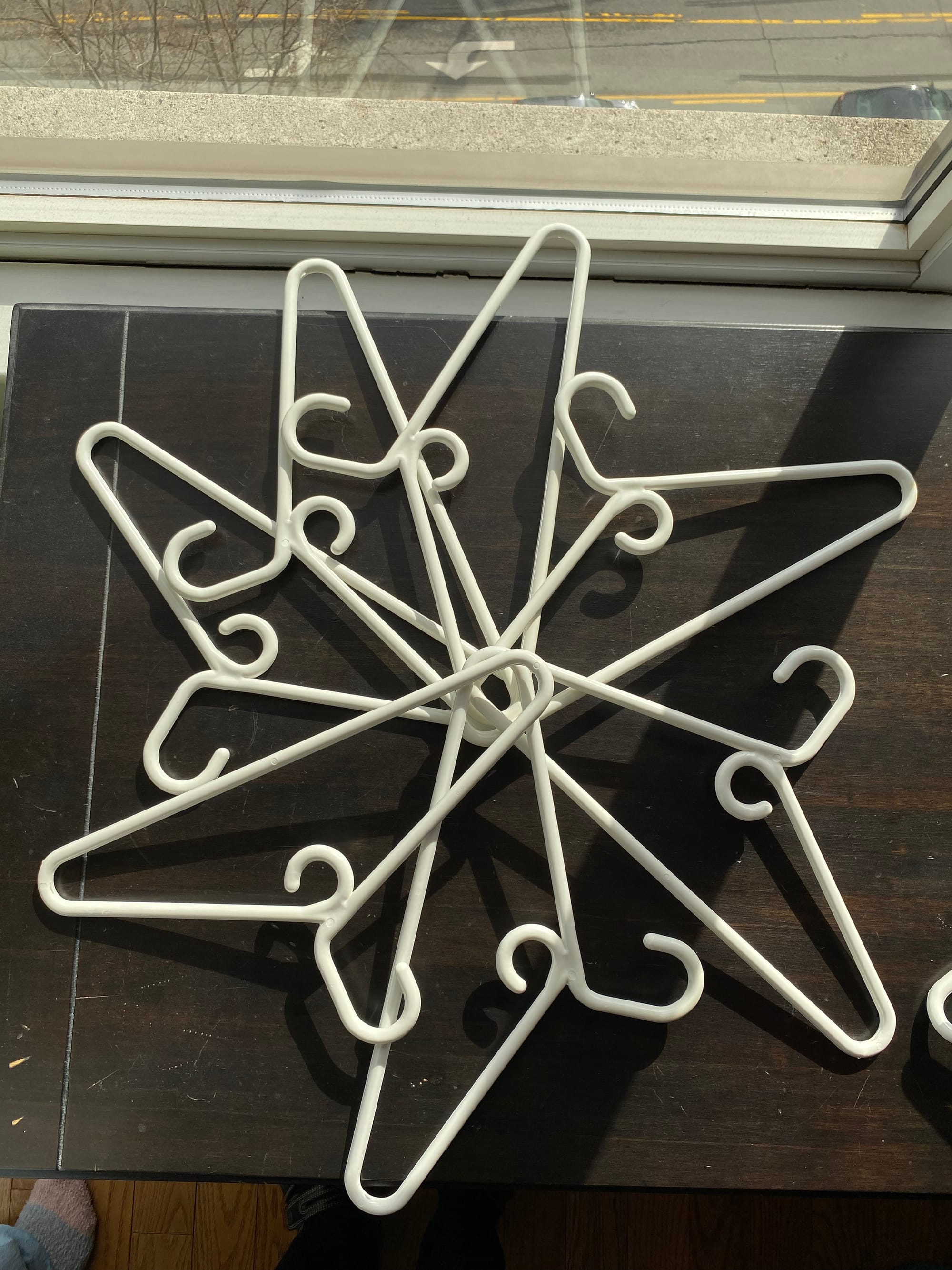 Seven white plastic hangers arranged in a snowflake formation.