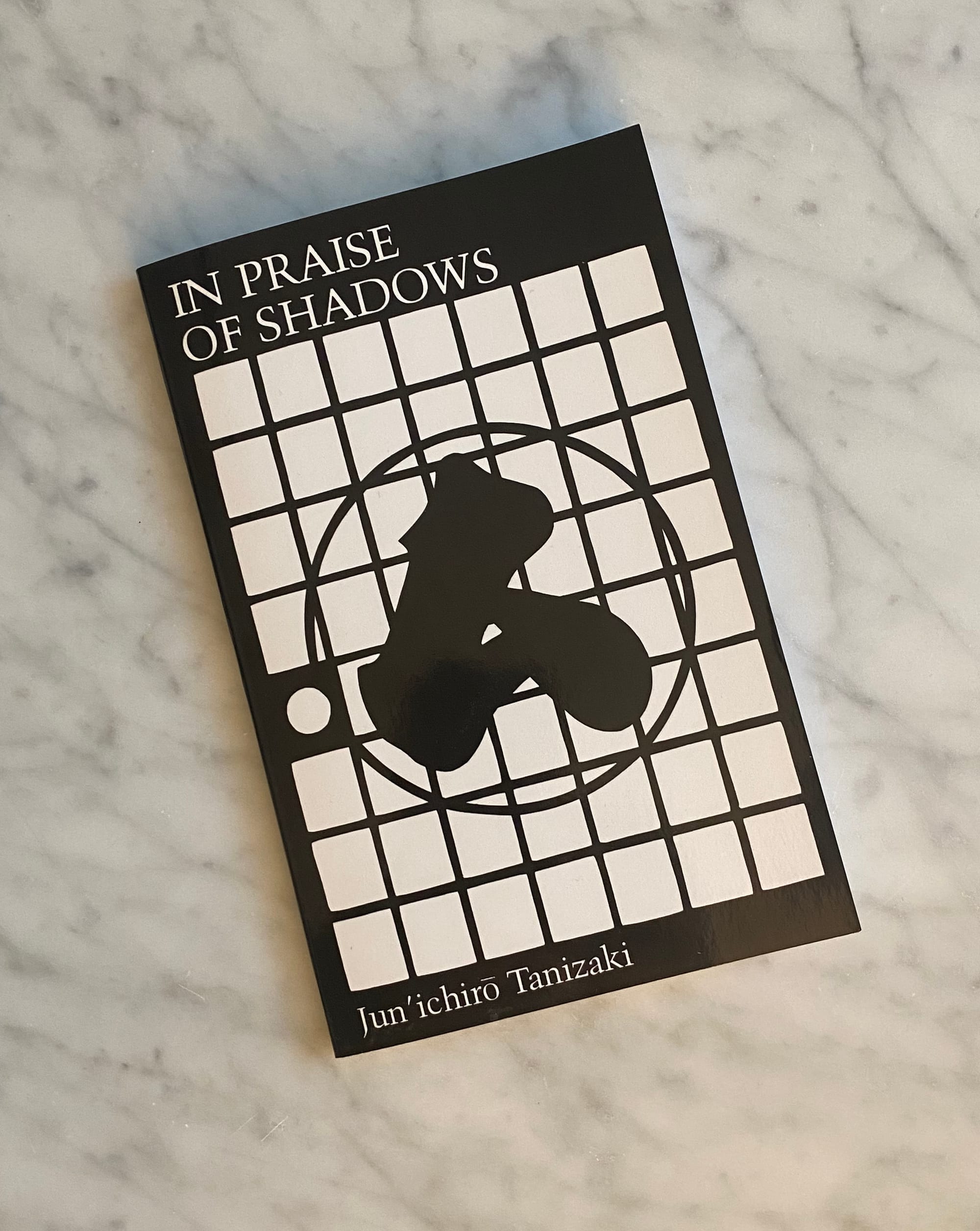 "In Praise of Shadows" book on a marble tabletop.