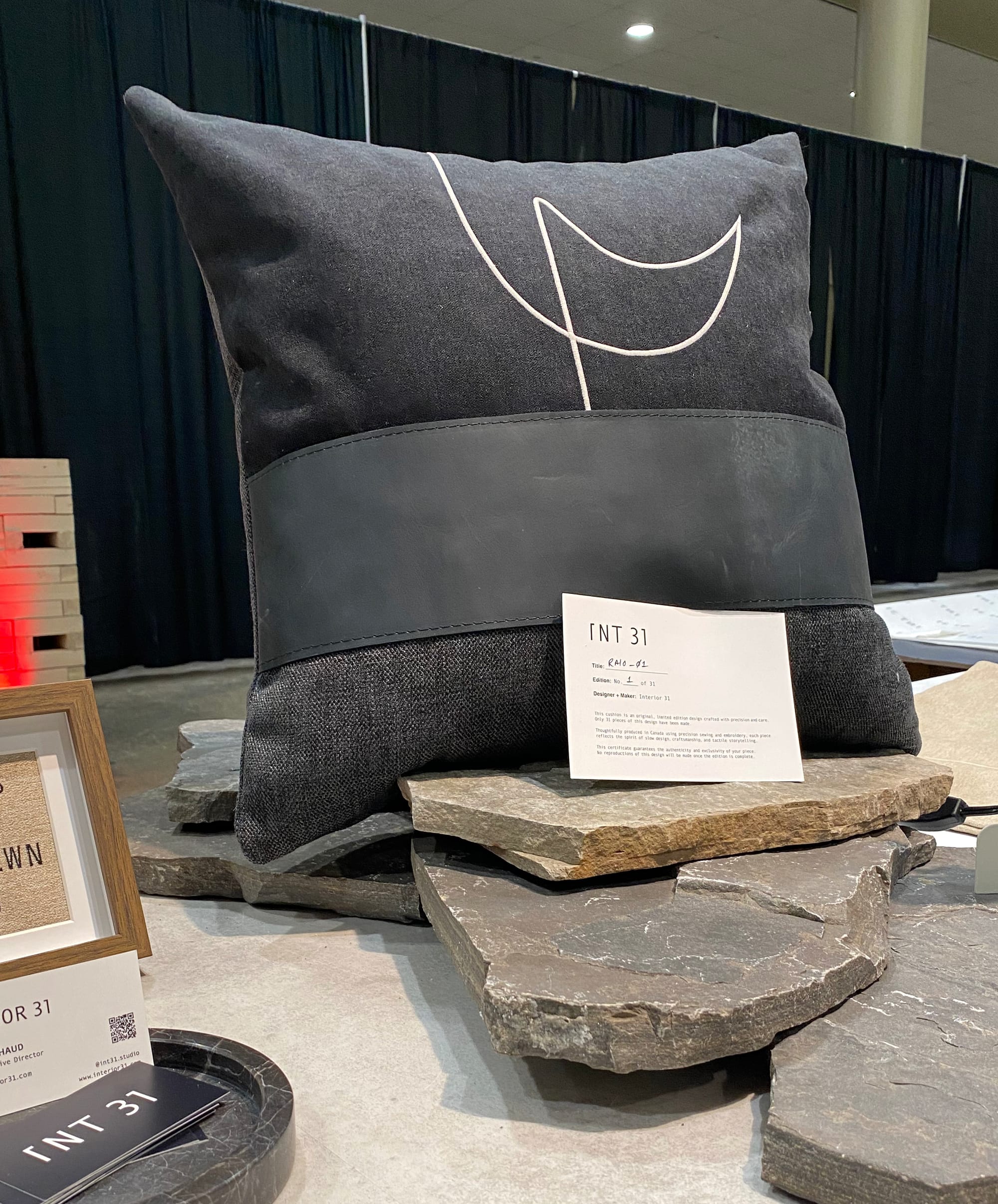 Large charcoal gray cushion with white embroidered lines.