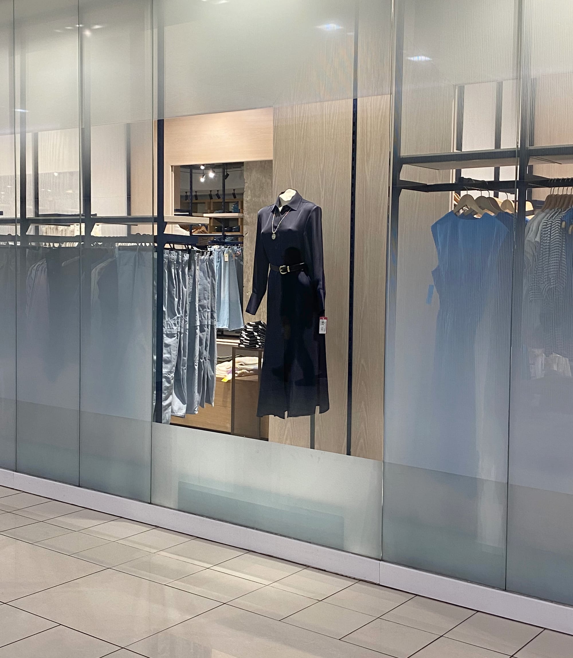 A black dress on a mannequin in a store window.