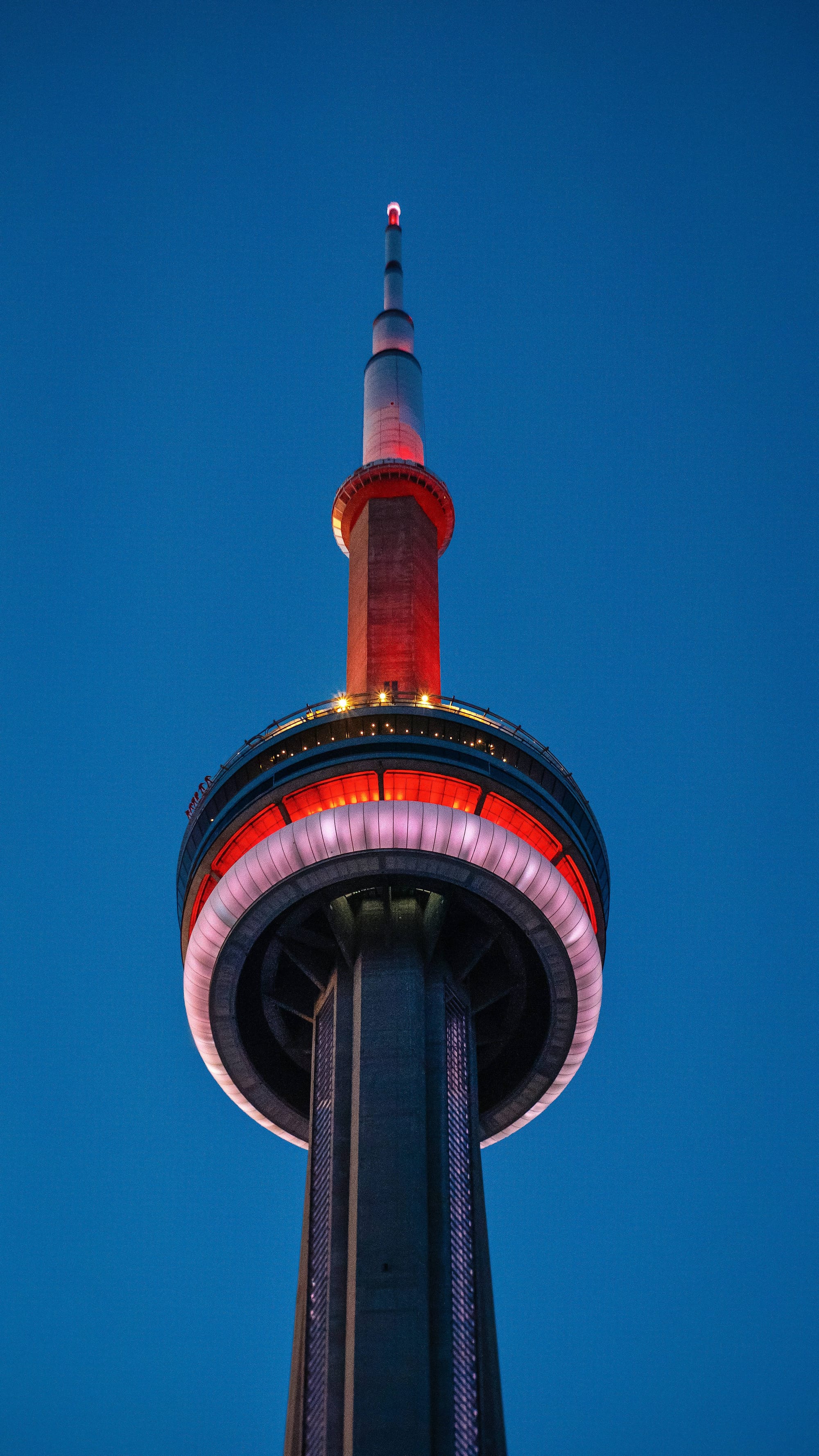 Top of the CN Tower lit up at night.