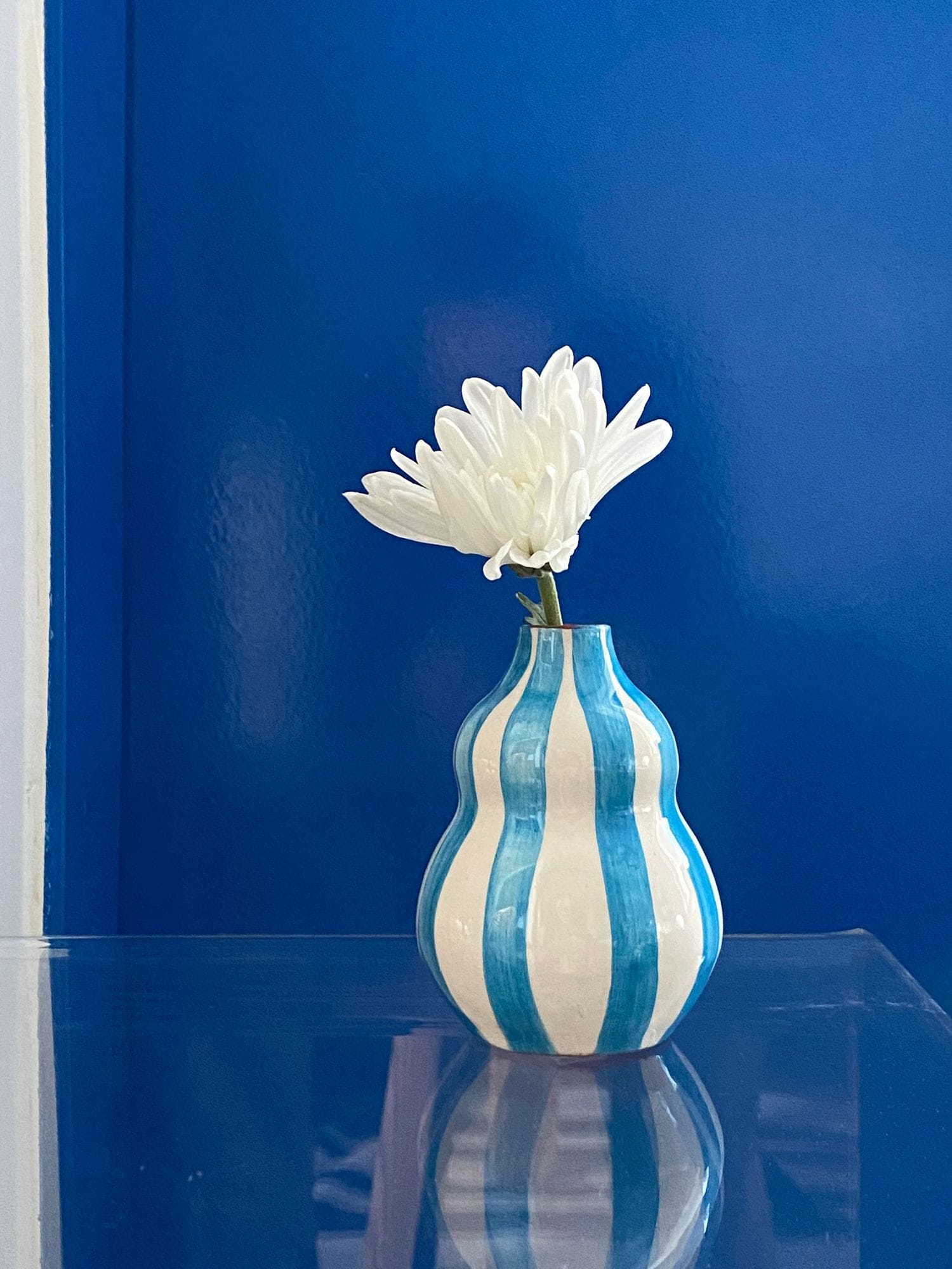 A small vase holding a single white daisy.