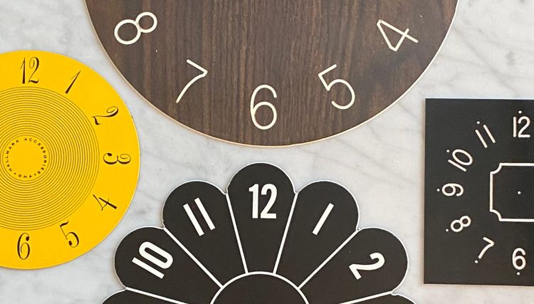 Four clock faces on a marble table top.