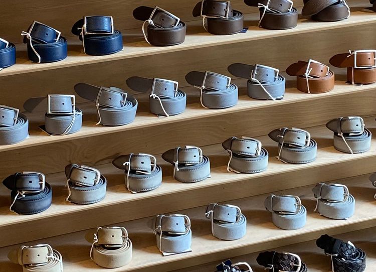 Belts neatly curled in spiral formations and arranged on shelves.
