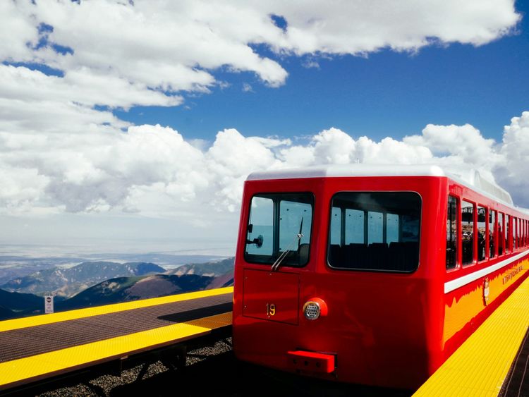 Red tram with yellow platforms on either side and a blue sky in the background.