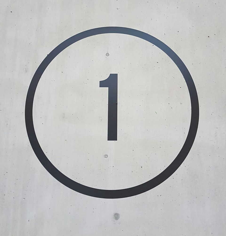 A number one inside a circle with a concrete background.