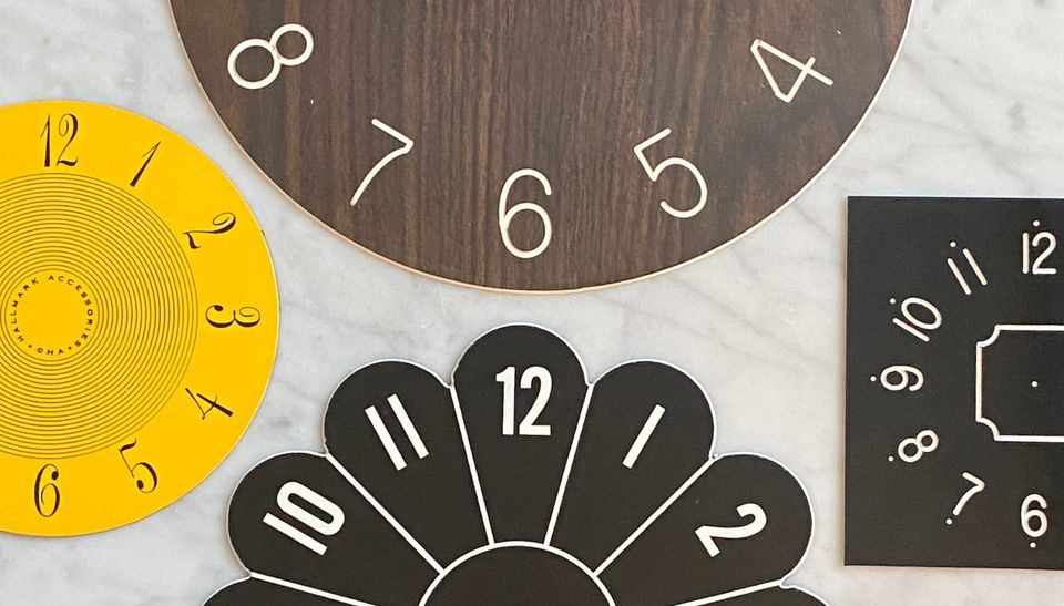 Four clock faces on a marble table top.