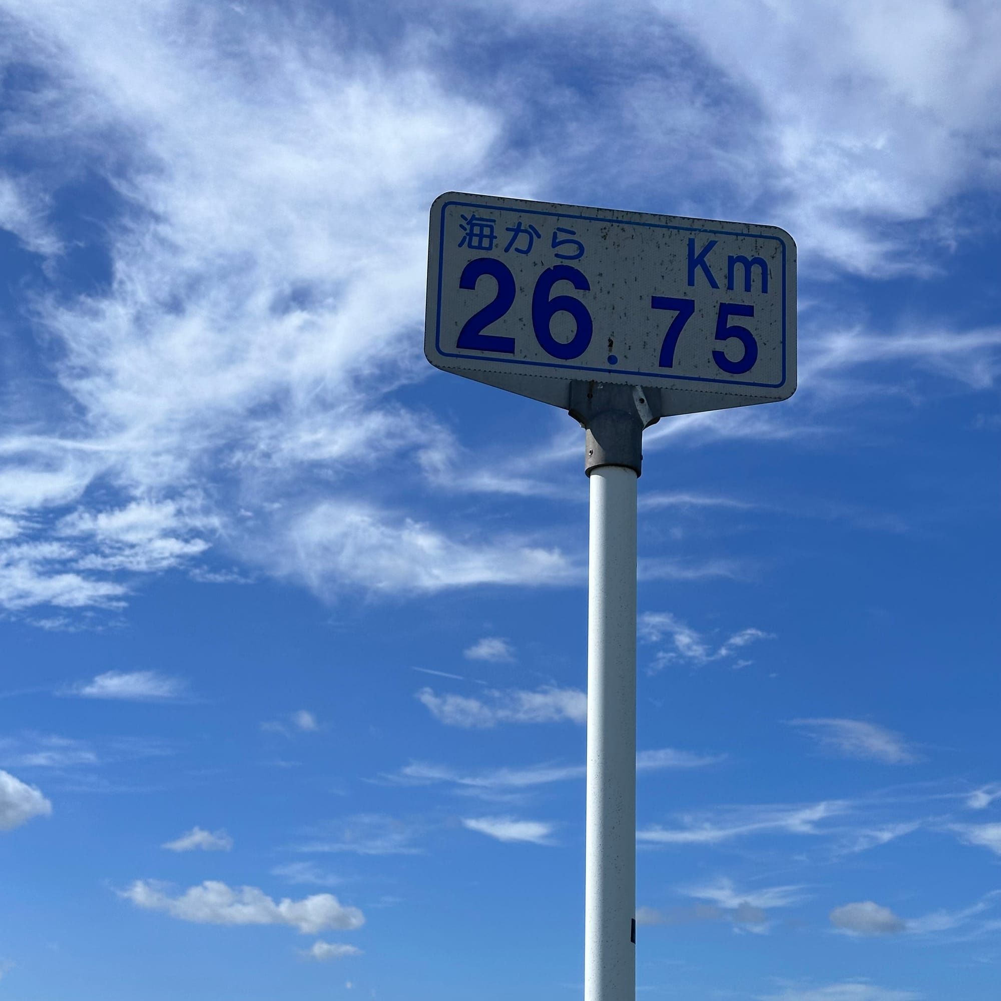 A kilometer marker sign showing 26.75 km to the see (in Japanese)