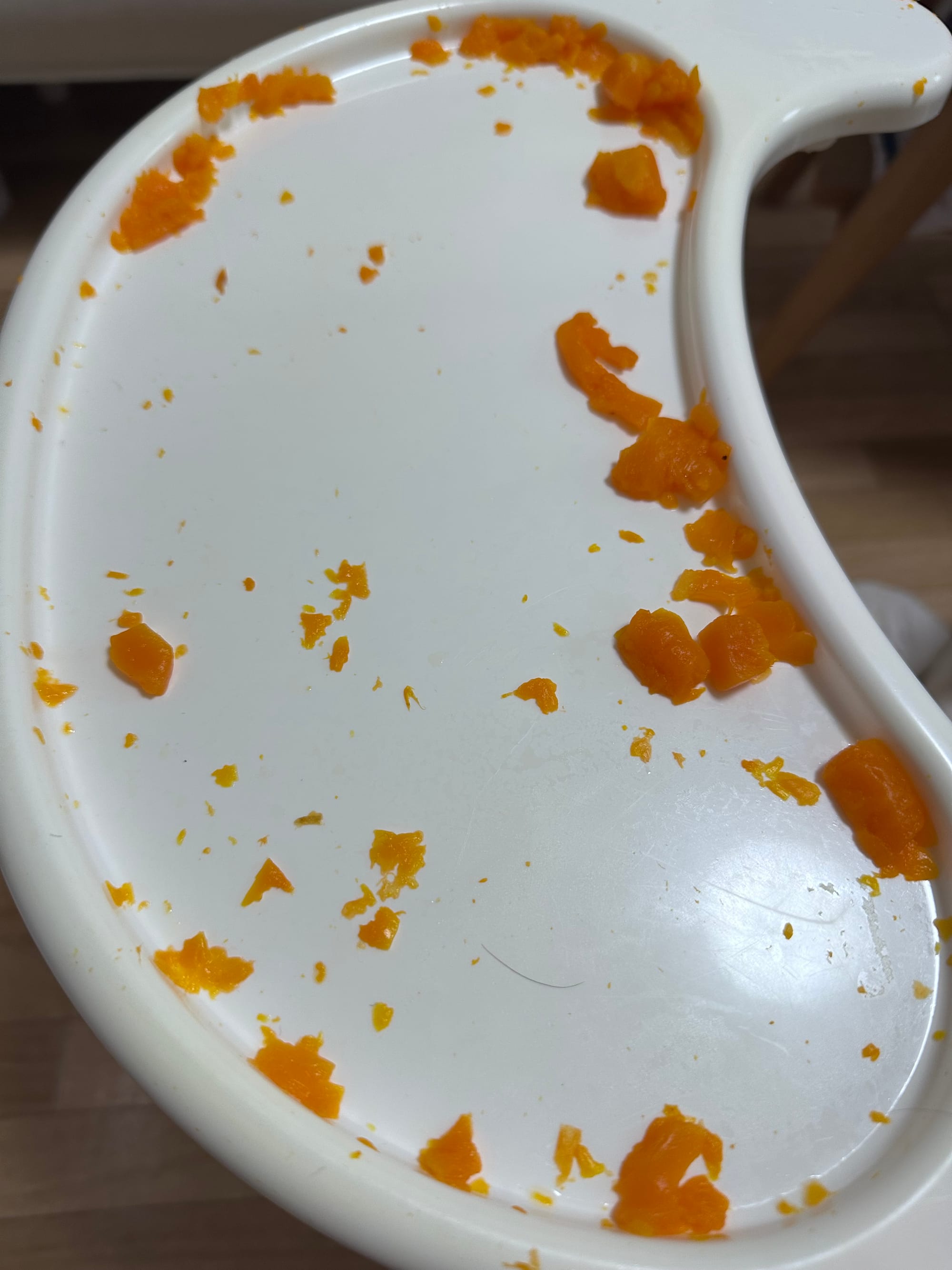 The tray of a baby chair covered with demolished carrot pieces