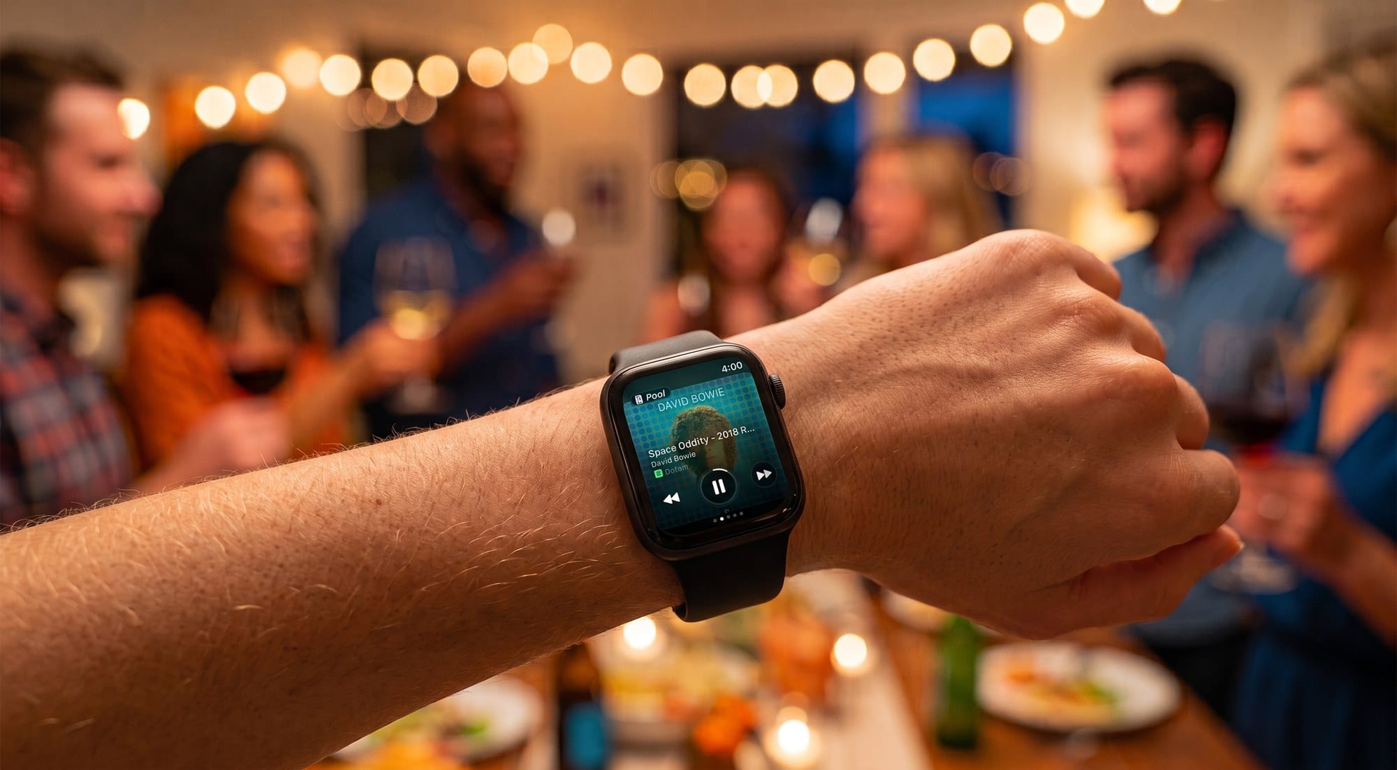 Someone at a house party controlling the host's Sonos from Nudge on their Apple Watch