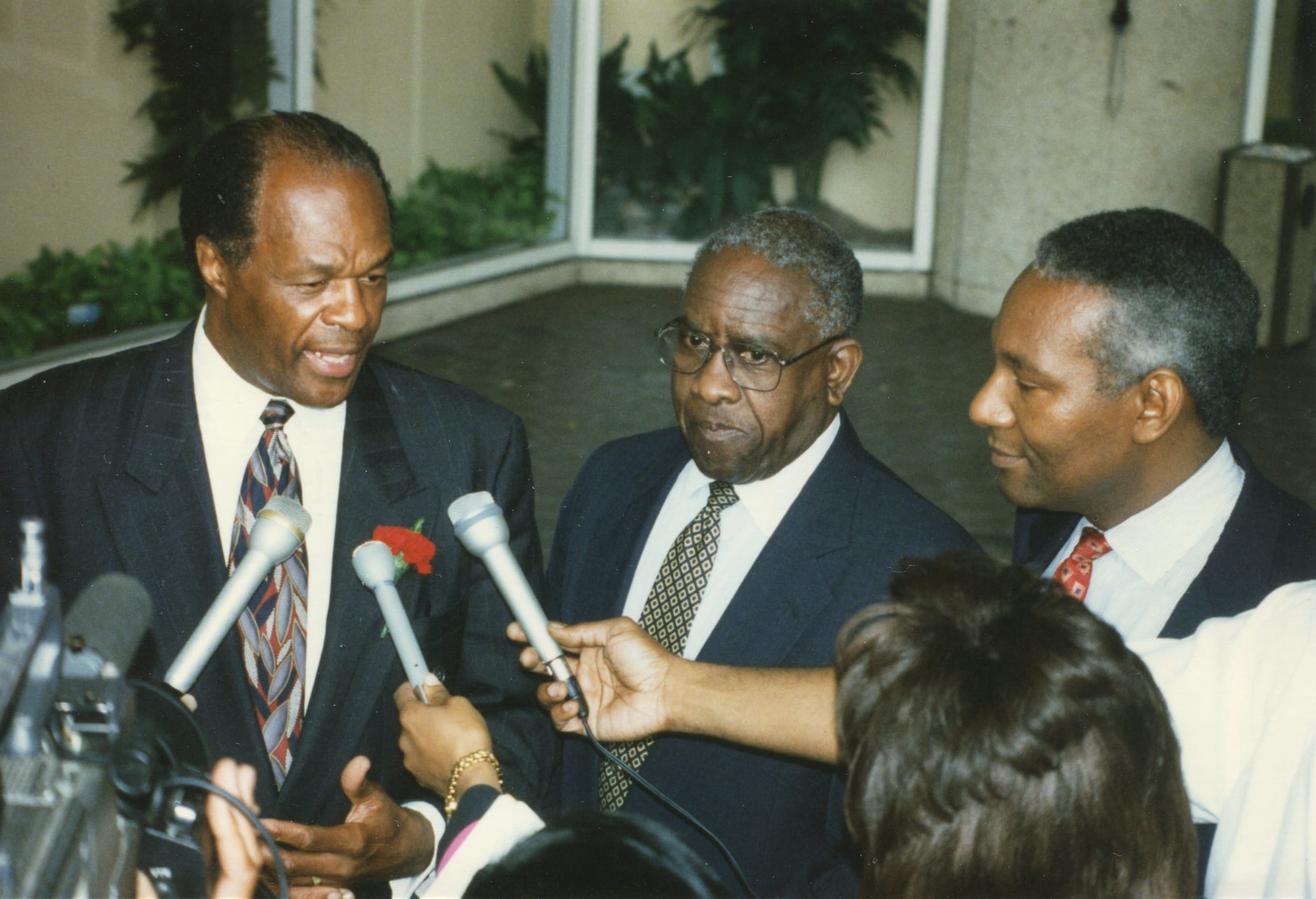Mayor Marion Barry, a Black man, being flocked by reporters holding microphones up to him. 