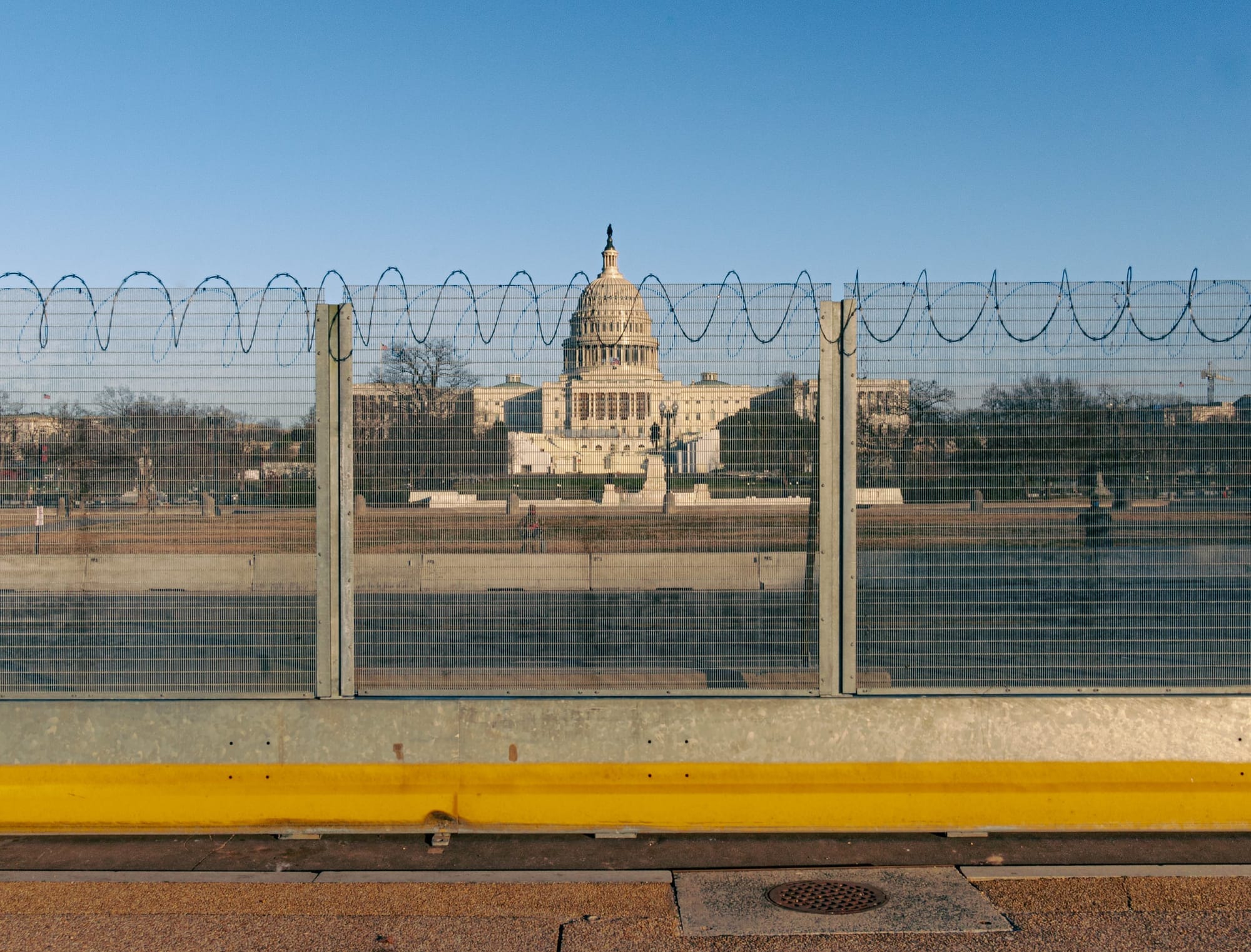 An image of the U.S. Capitol behind a barbed wire fence. 