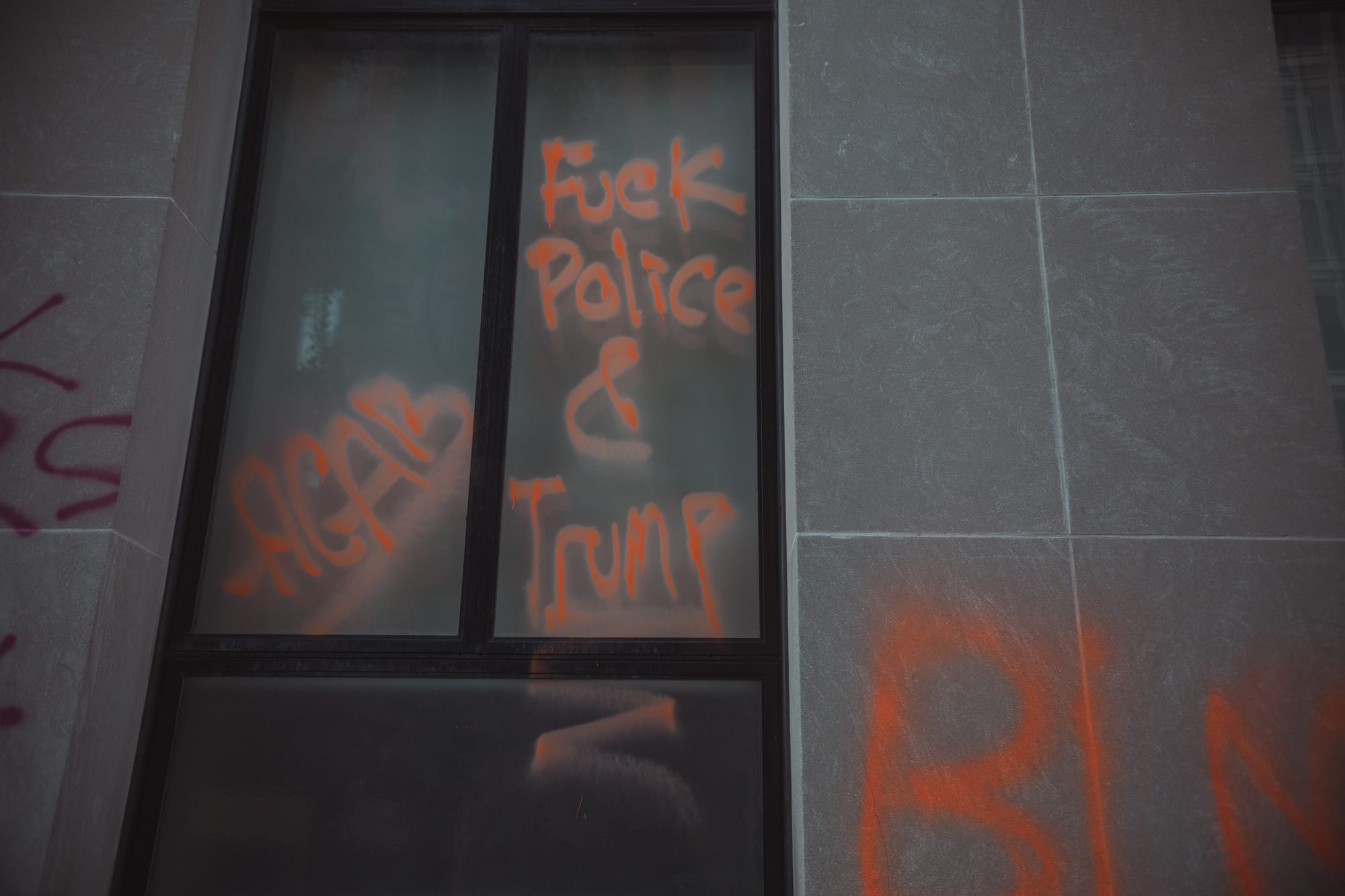 Graffiti on a building reads "Fuck police & trump" and "ACAB." 