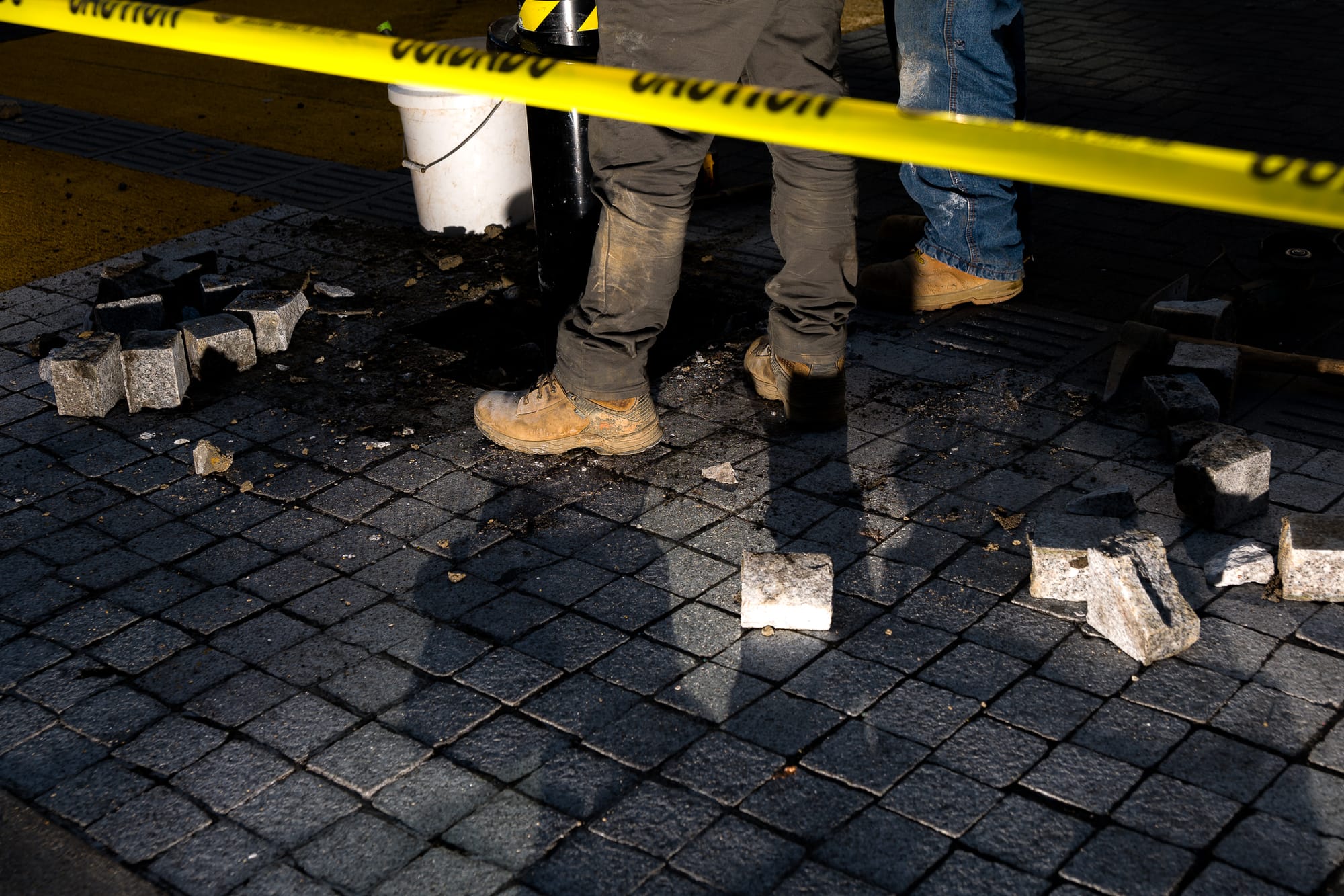 Crews stand over brick streets while drilling and digging up the ground. 