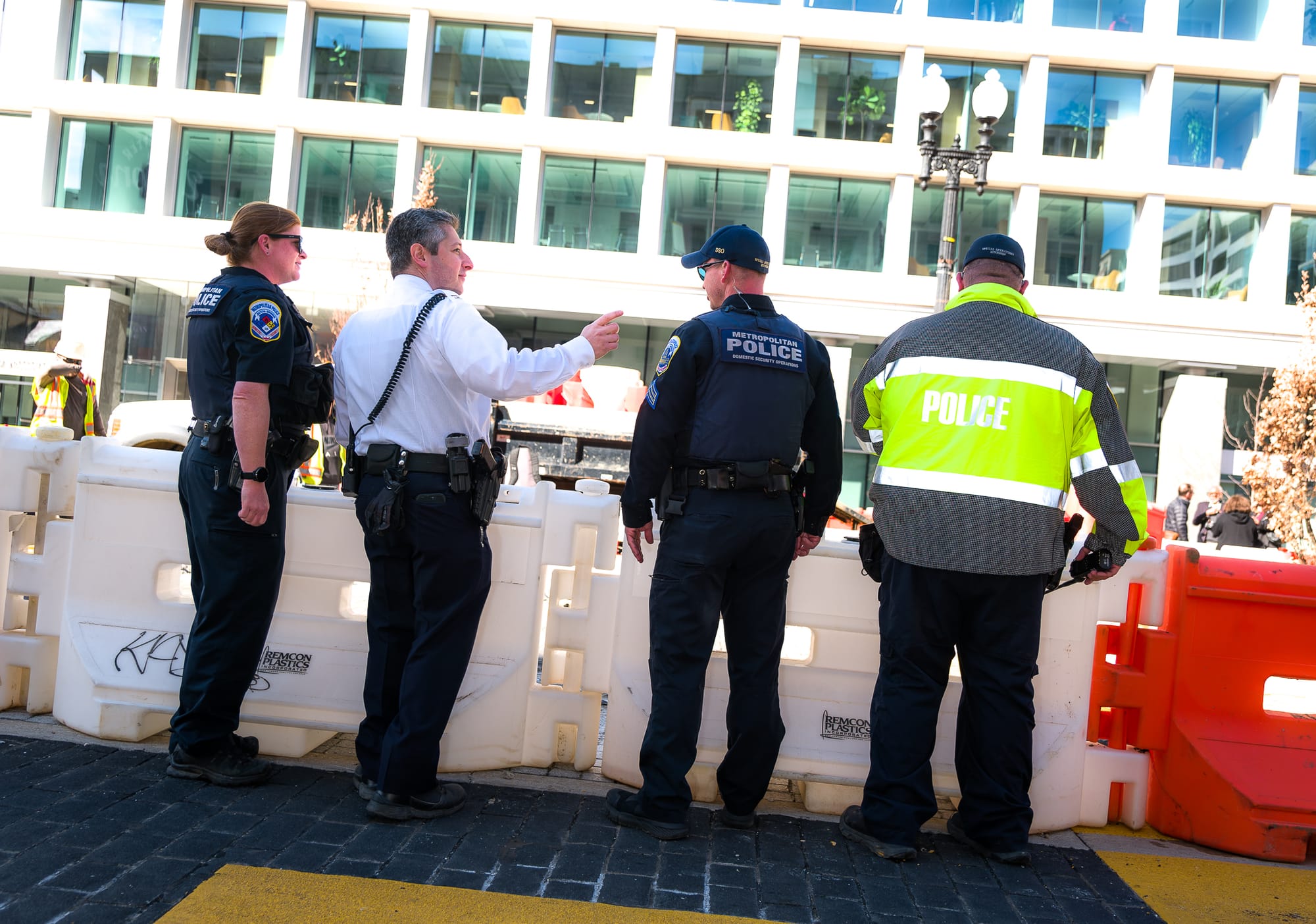 Four police officers stand with their backs to the camera during the demolition.