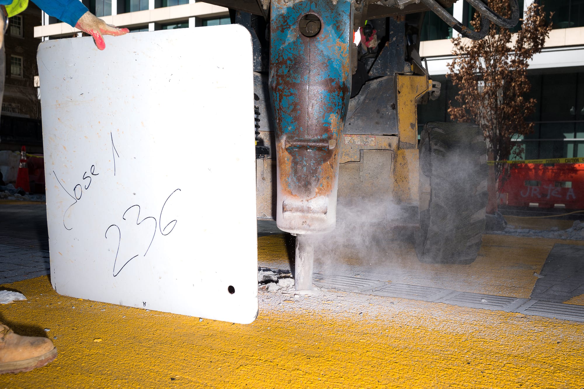 A machine drills into yellow paint in the ground. 