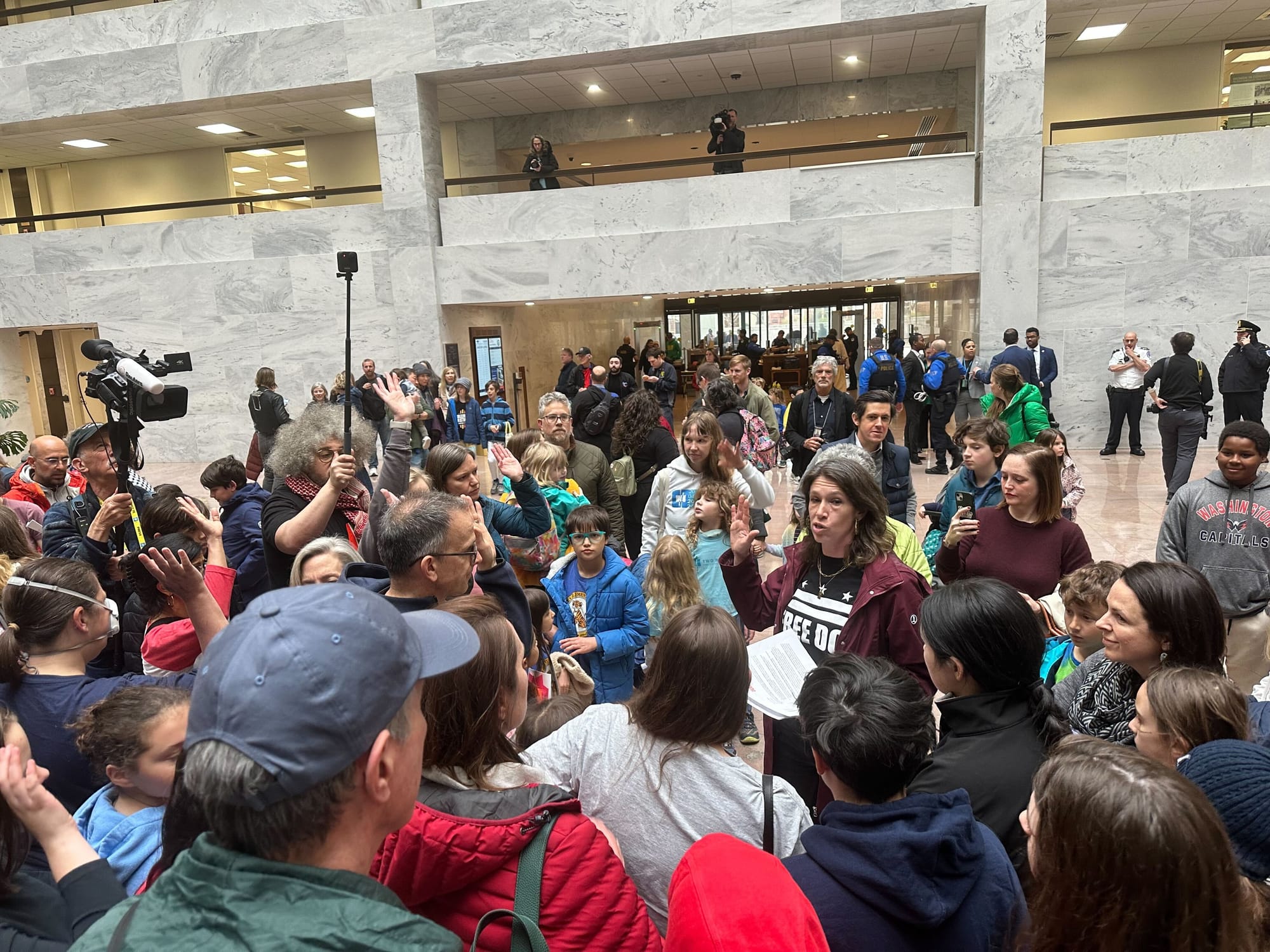 A crowd of people gather in the halls of the senate listening to one person with a "Free DC" shirt.