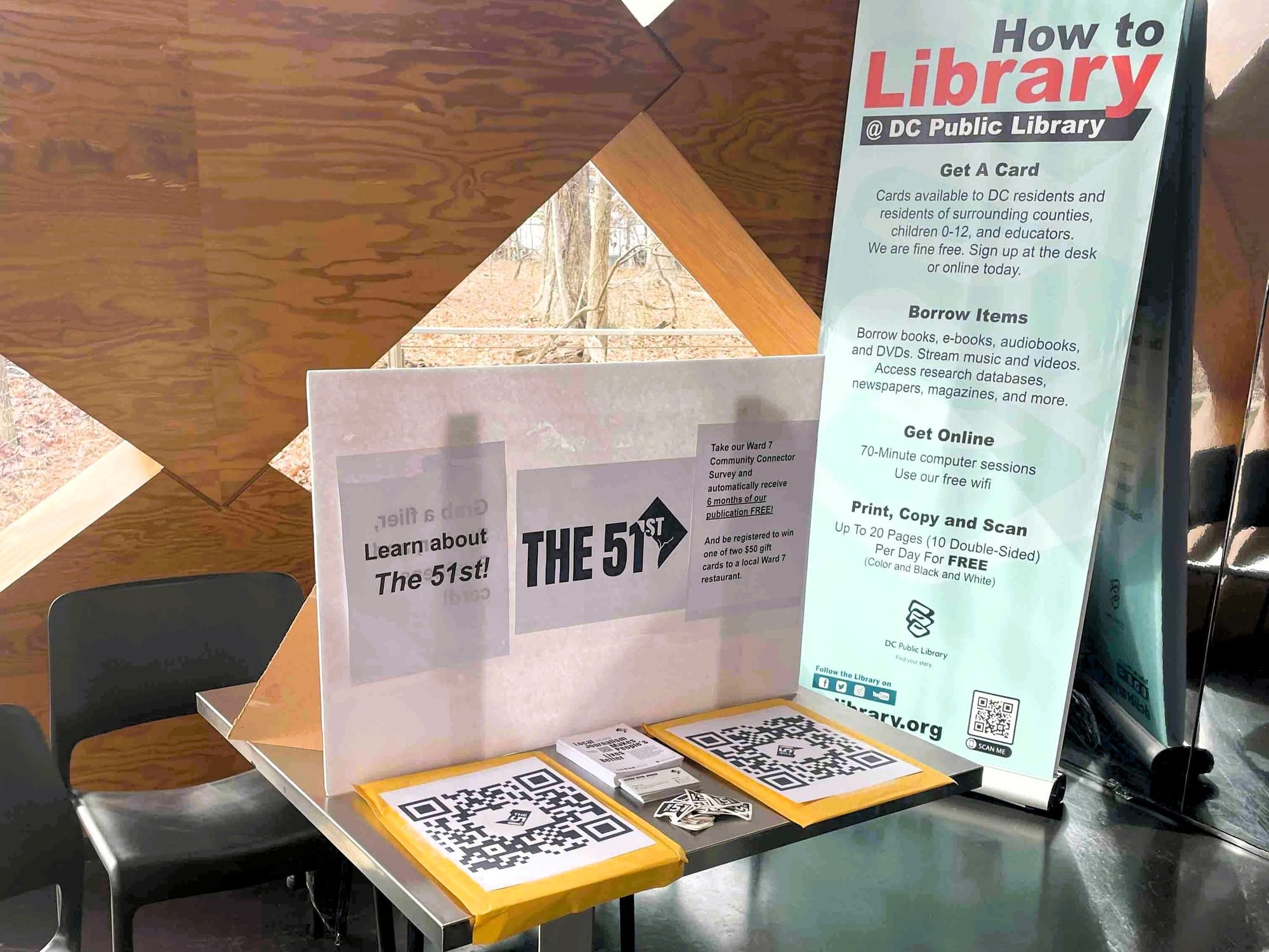A table with materials about The 51st, including two QR codes, at the Francis A. Gregory Library.