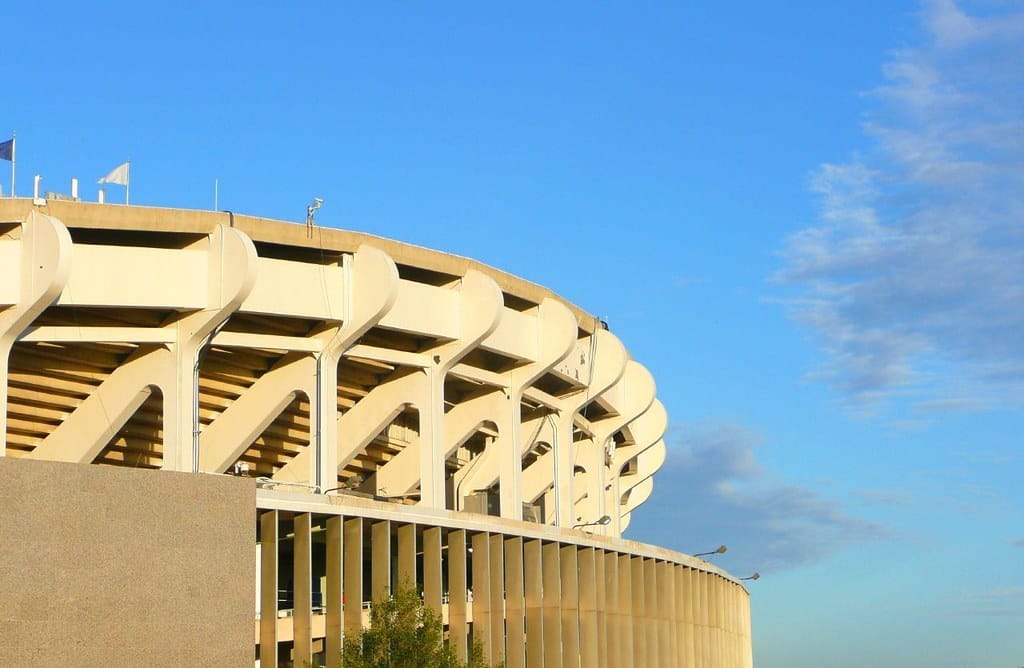 The top of a white stadium in front a clear blue sky. 
