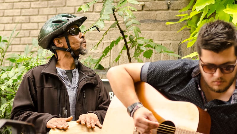 A picture of someone playing guitar and another person playing the drums.