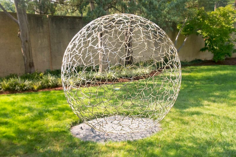 A round sculpture in the middle of a lawn.