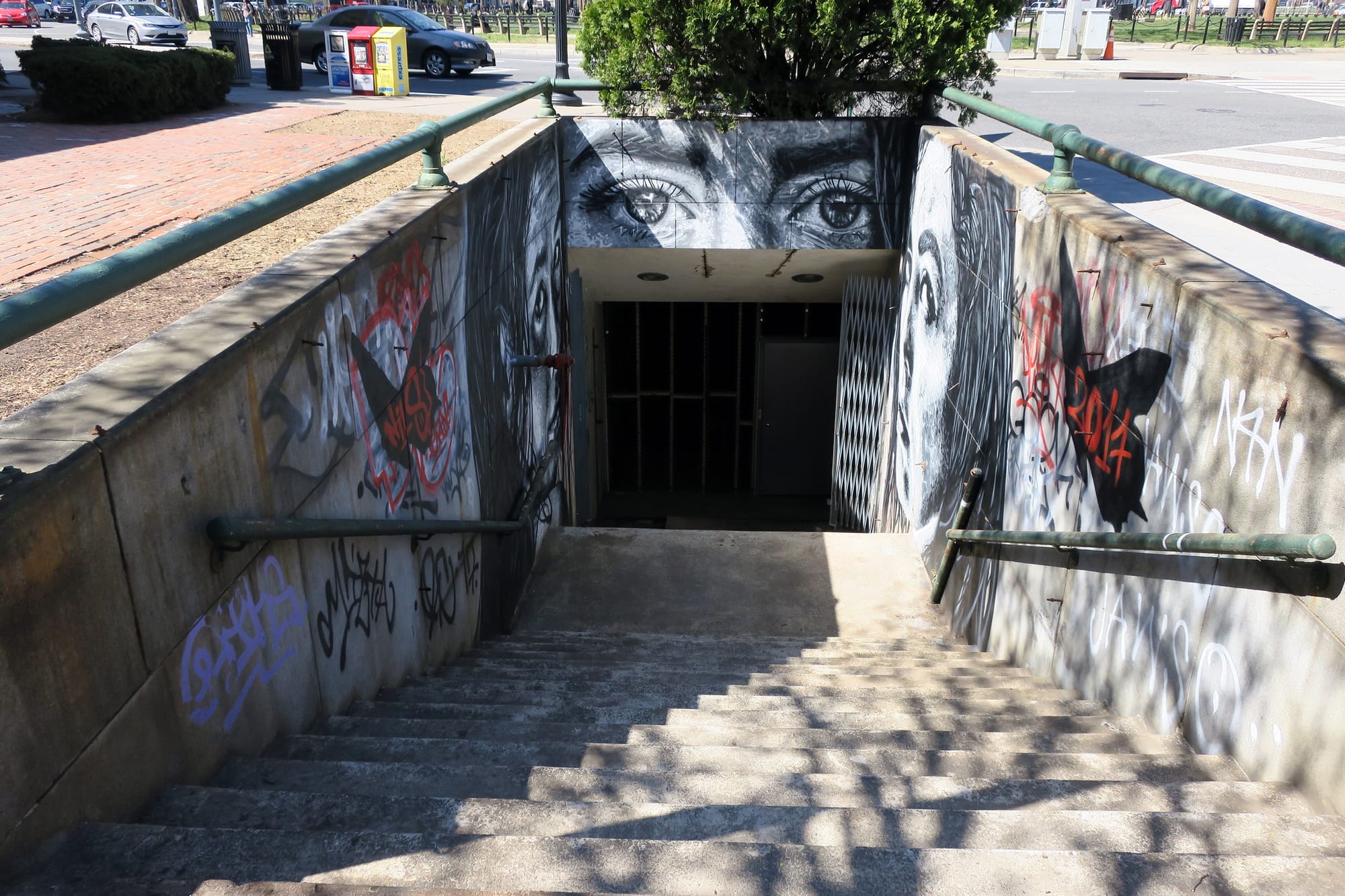 Concrete stairs with art work on the sides lead down into a dark door. 