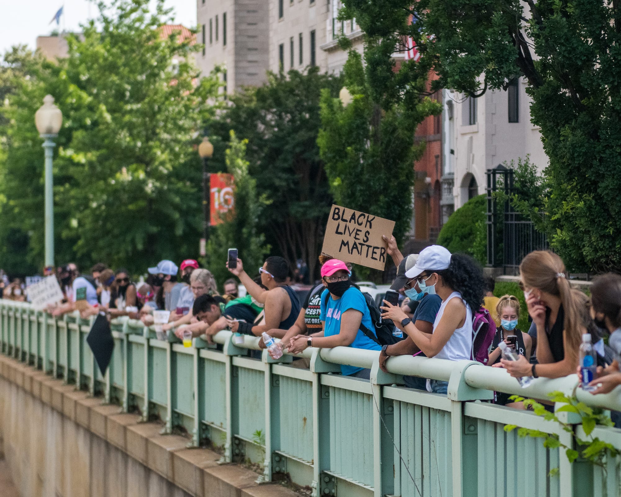 Protesters stand along a roadway in D.C., one holds a BLACK LIVES MATTER sign. 