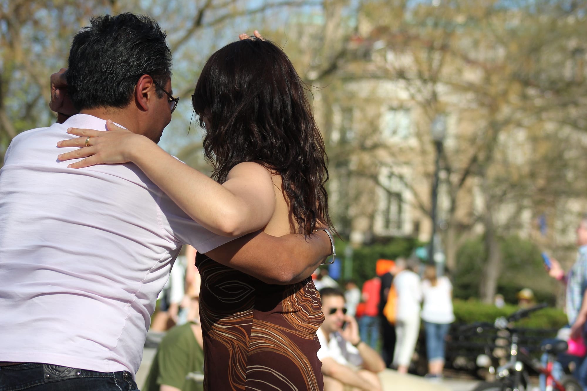 A couple dancing in the park, facing away from the camera.