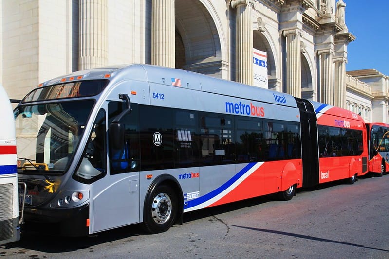 A red, gray, and blue Metrobus parked outside of Union Station. 