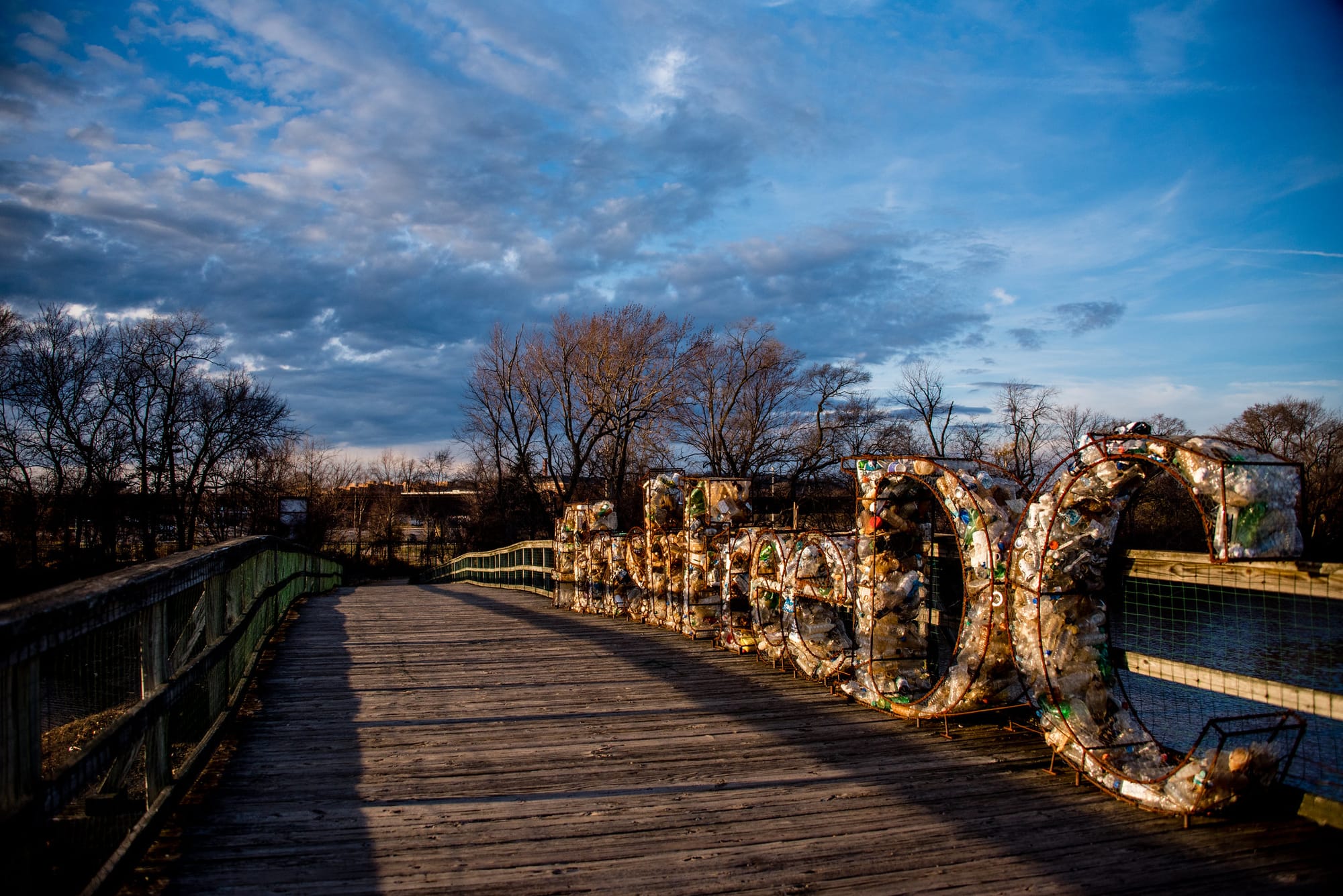 An image of a trash-art installation on a bridge over water. 