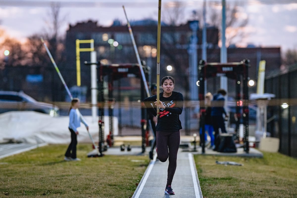 A woman runs forward with a pole, ready to vault. 
