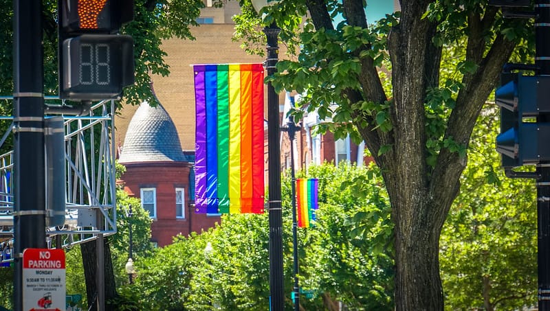 A Pride flag hangs from a streetlamp. 