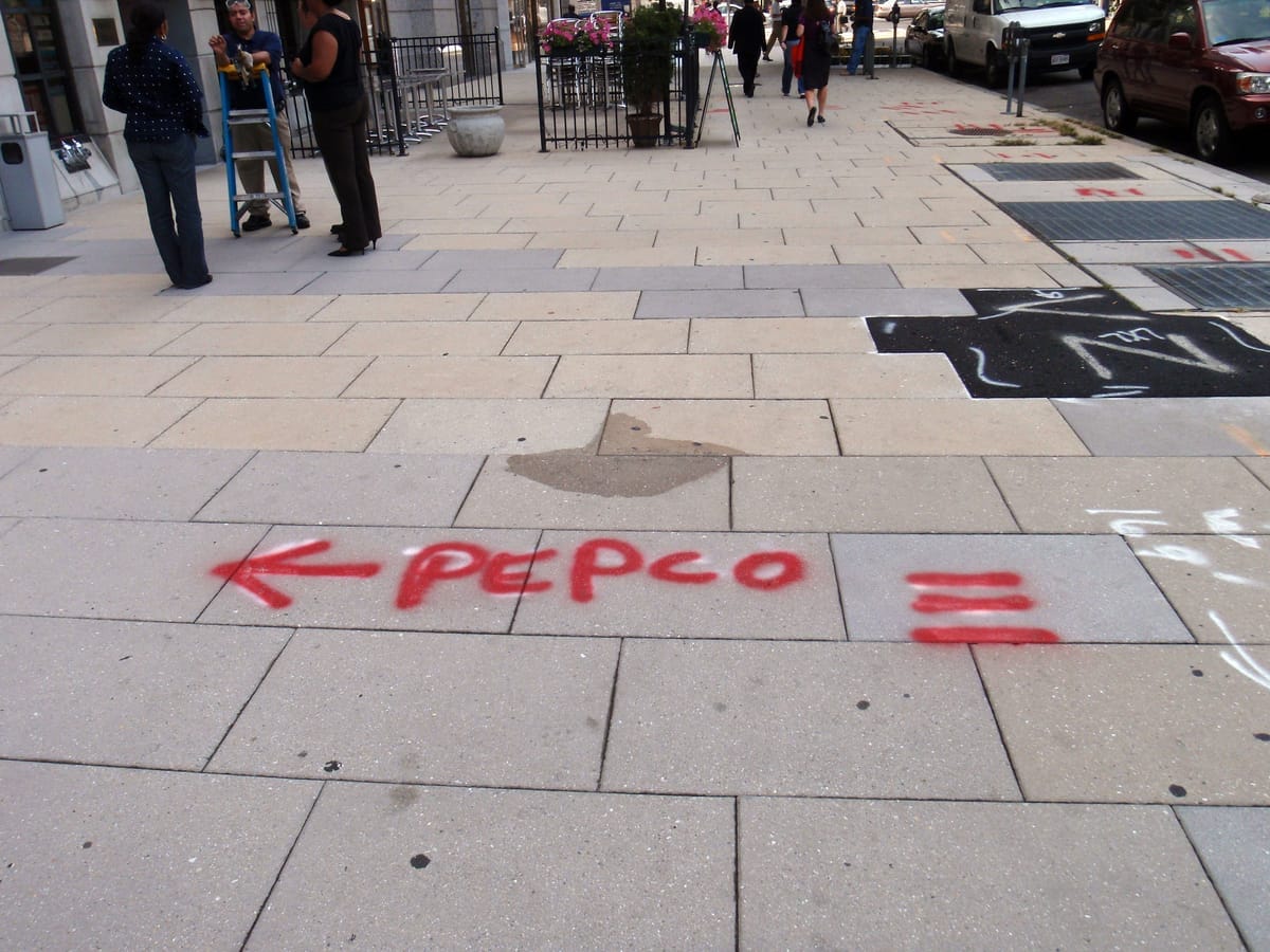 A city sidewalk with the word Pepco spraypainted in red.