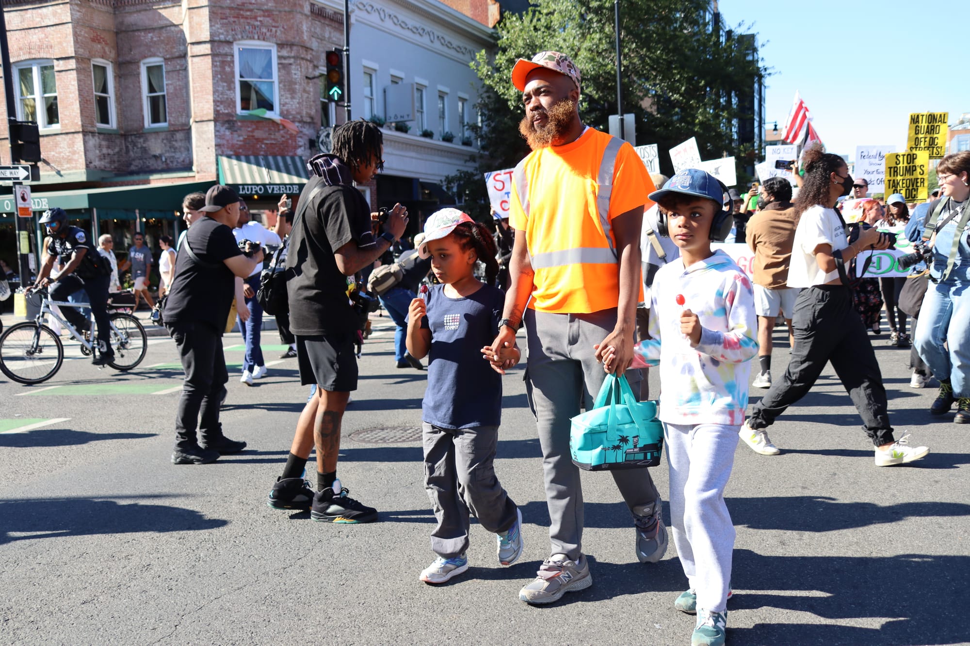 A father holding the hands of his two children marching in a protest on 14th Street.