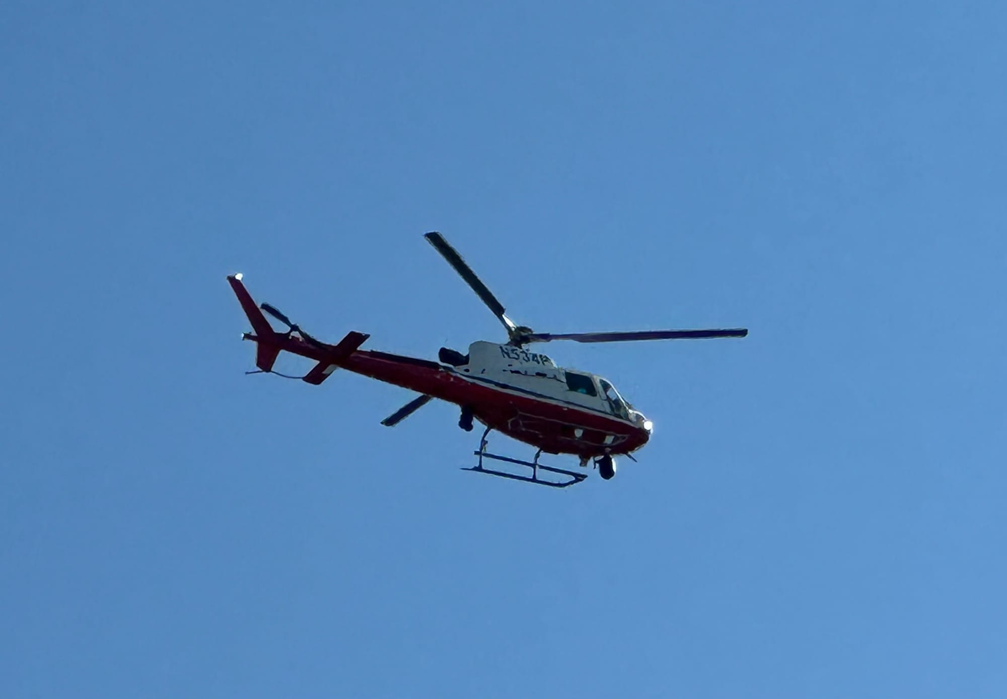 Photo showing a red and white helicopter in the sky