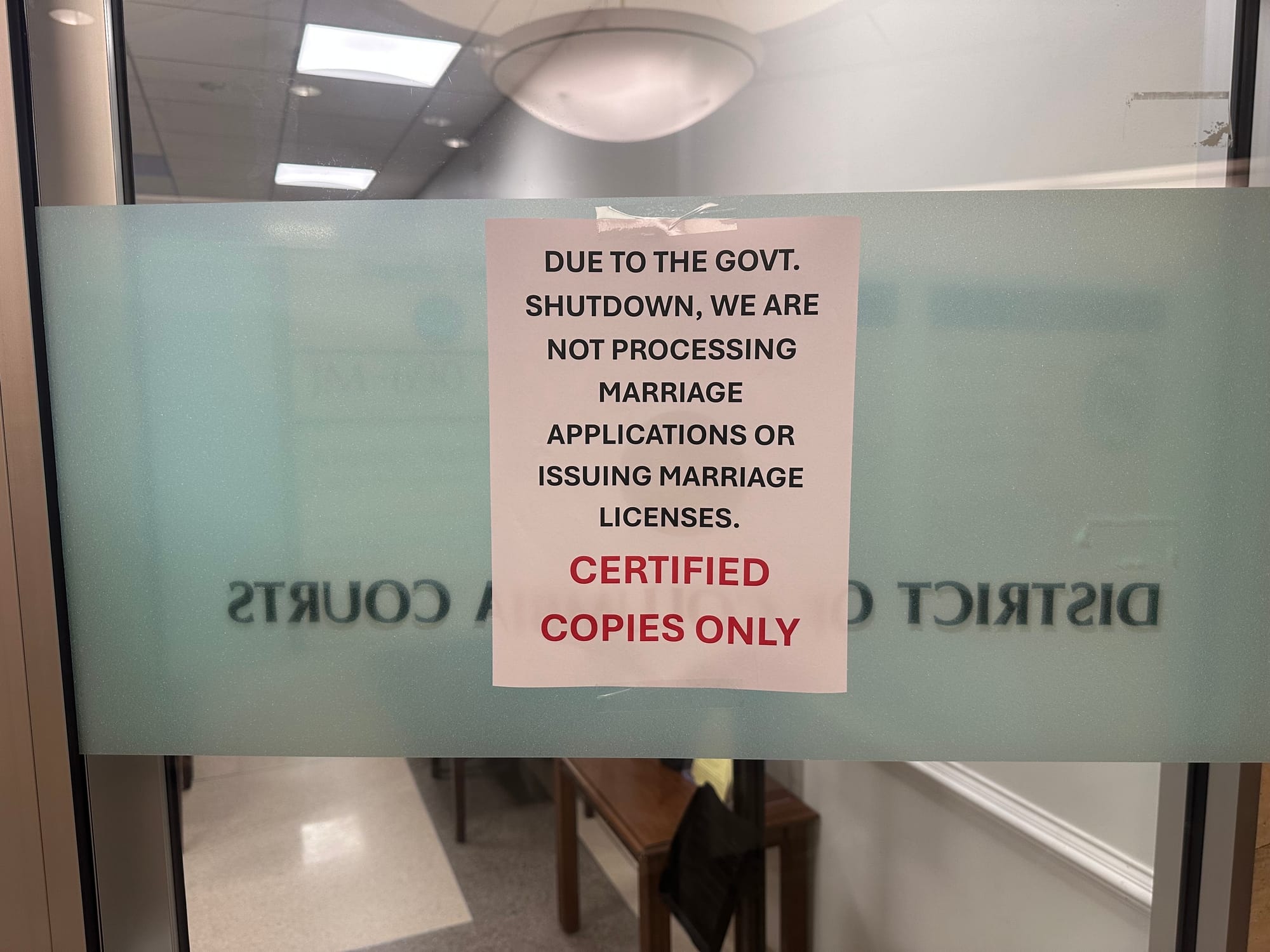 A sign reads "Due to the govt. shutdown, we are not processing marriage applications or issuing marriage licenses. Certified copies only." 
