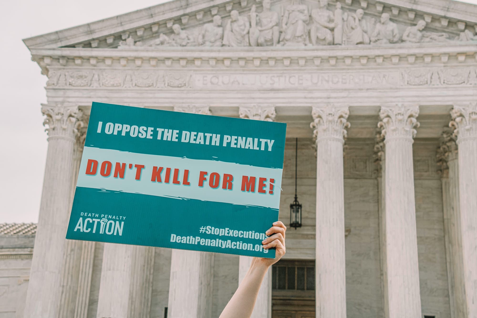 A person holds up a sign in front of the Supreme Court that reads "I oppose the death penalty. Don't kill for me!"