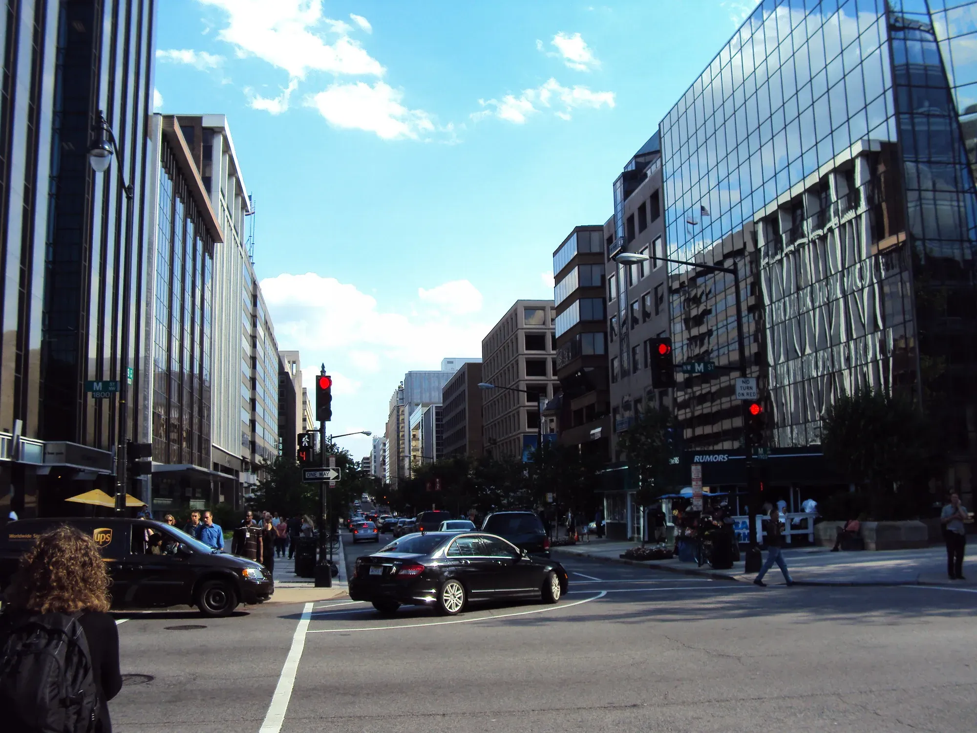 A stretscape on a sunny day, with cars and people milling around downtown D.C. 