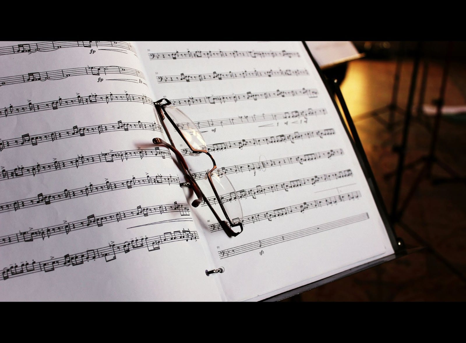Glasses rest precariously atop a binder of sheet music.