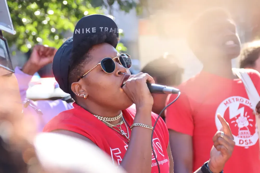 A person holding a microphone and speaking to a crowd